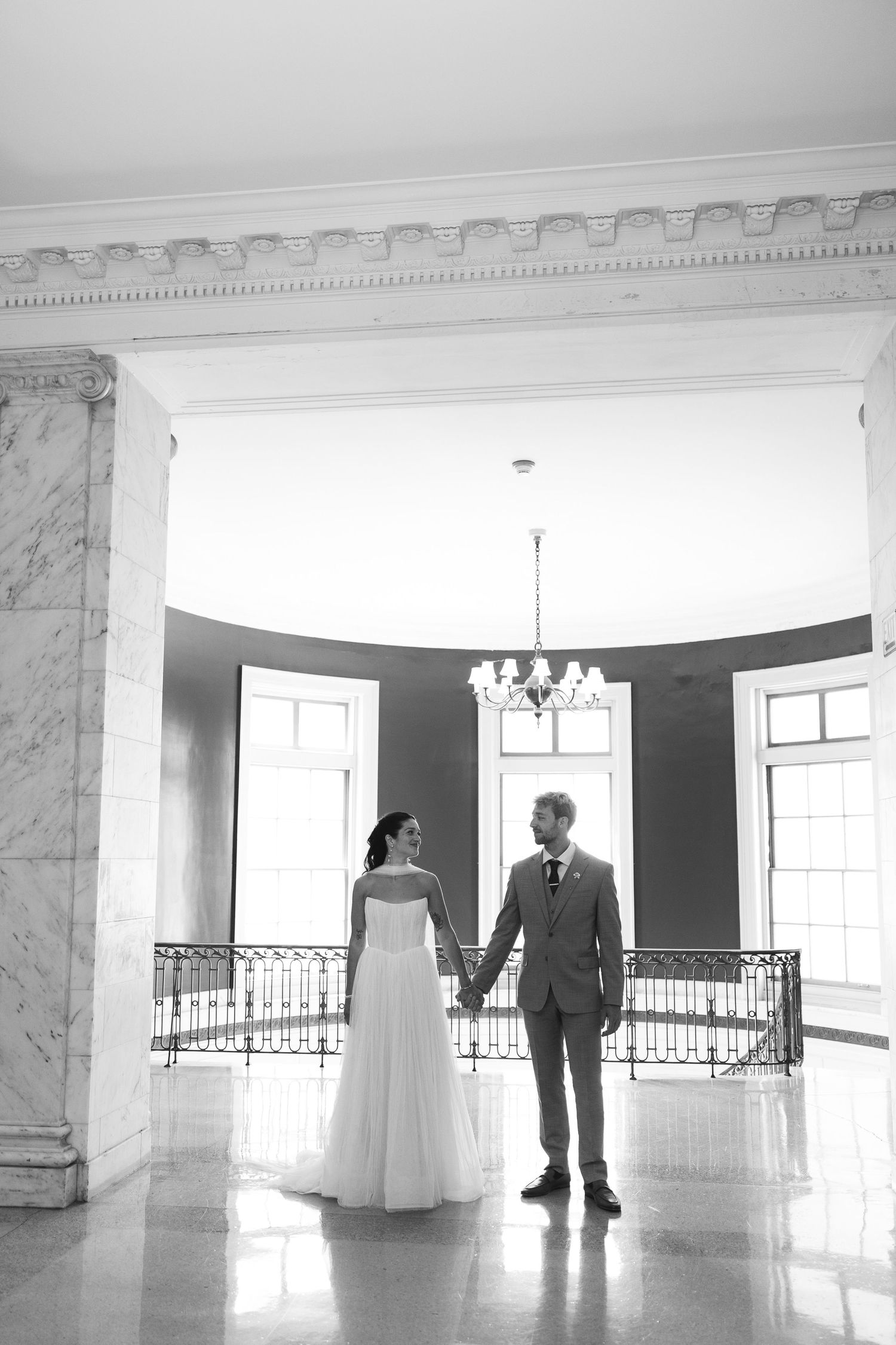 A black and white photo series showing silhouettes of a couple in a bright white elegant venue with ornate moldings.