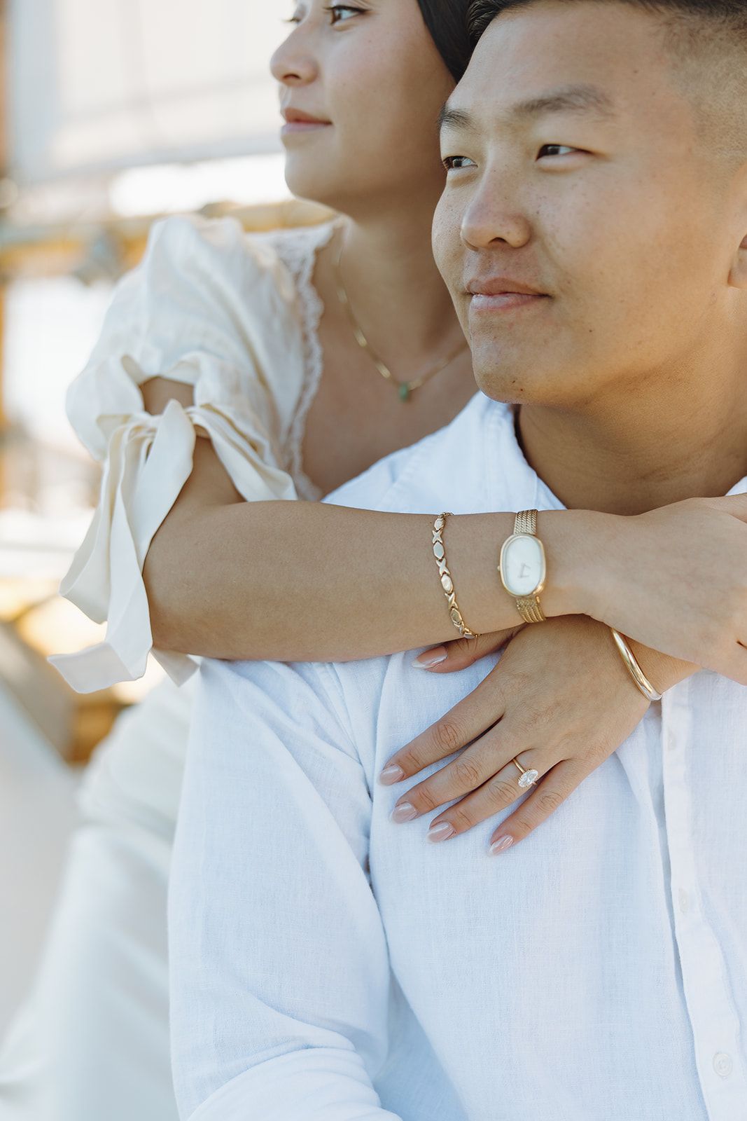 A couple in white clothing share an intimate embrace while standing together in a bright indoor setting.
