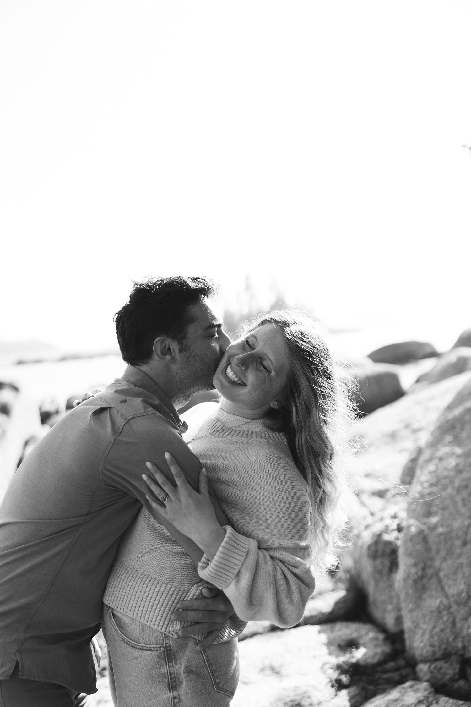 A couple embraces intimately on rocky terrain in a romantic black and white photo series.