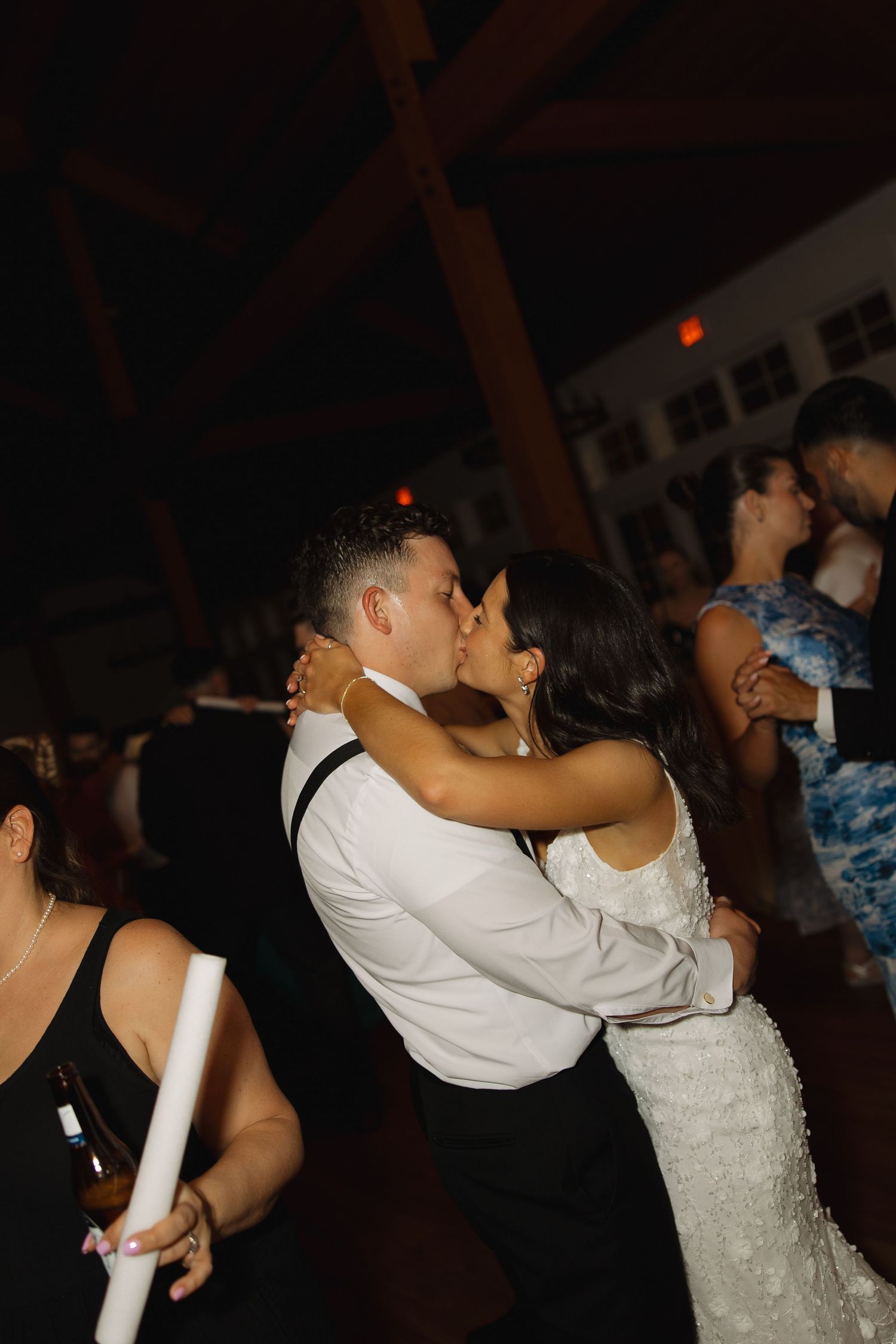 A couple shares an intimate dance moment at a wedding reception under dim lighting.