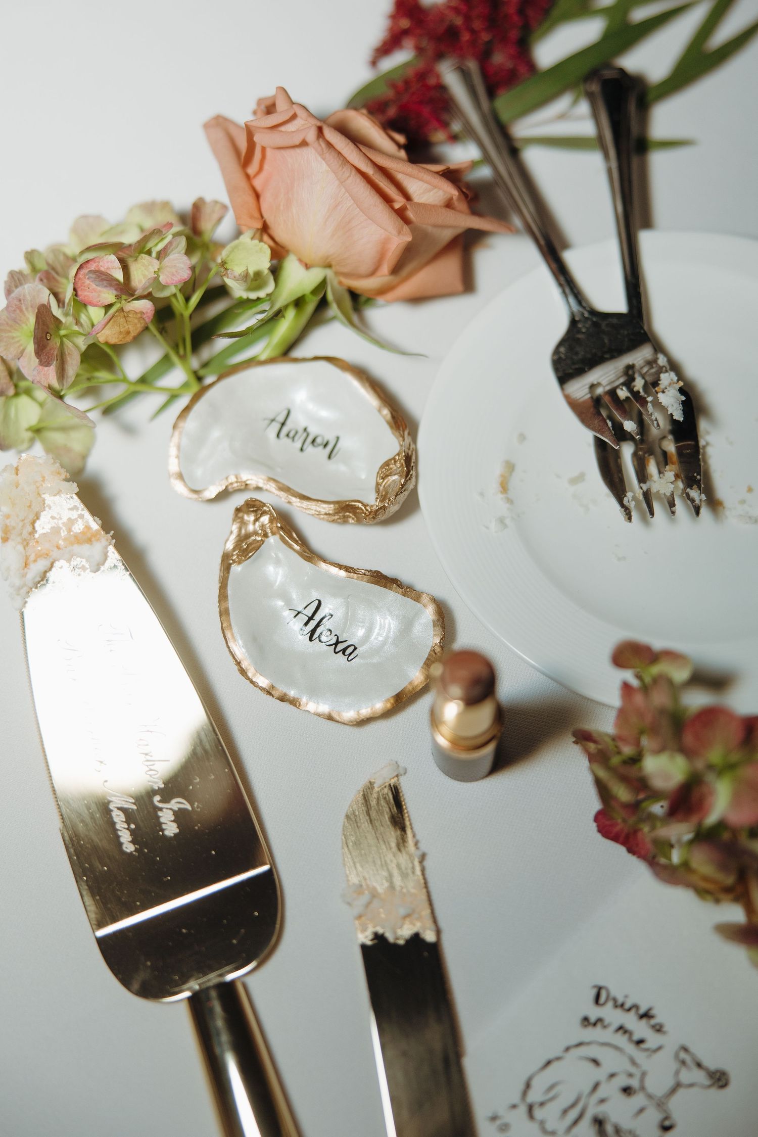 Vintage silver forks and spoons with delicate dried flowers arranged on a white surface in an artistic flatlay composition.