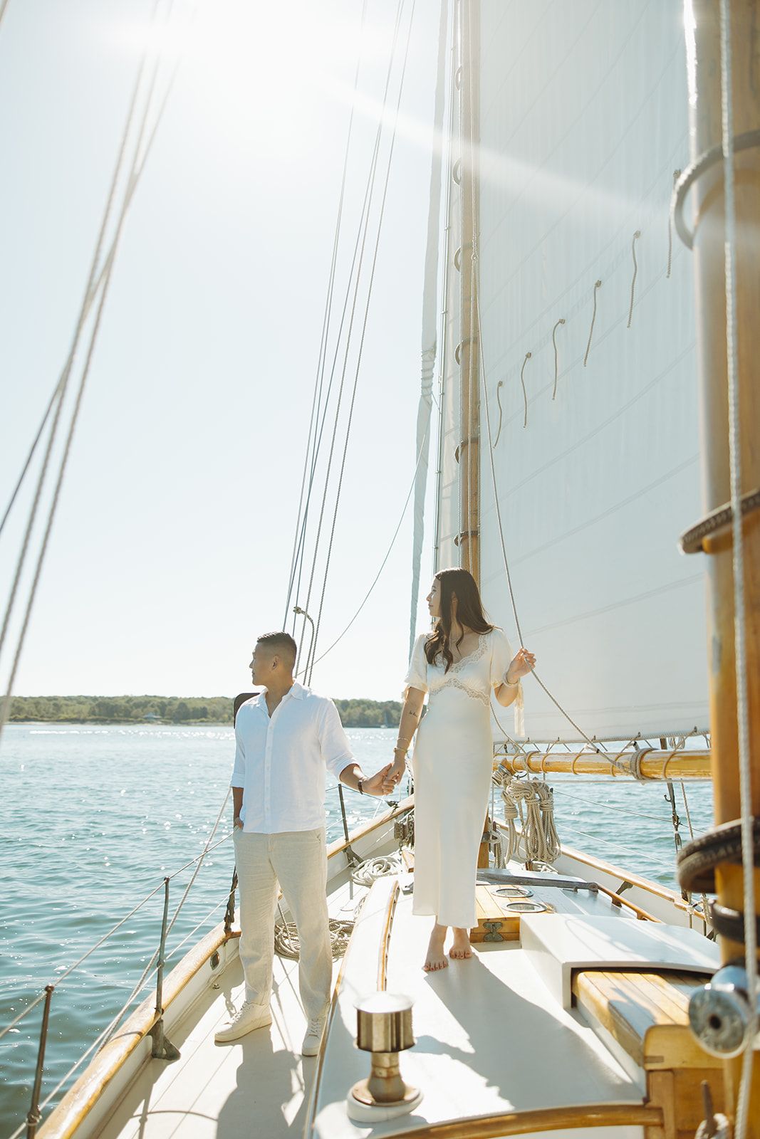 Passengers enjoy a sunny day sailing on a yacht with white sails against blue ocean waters.