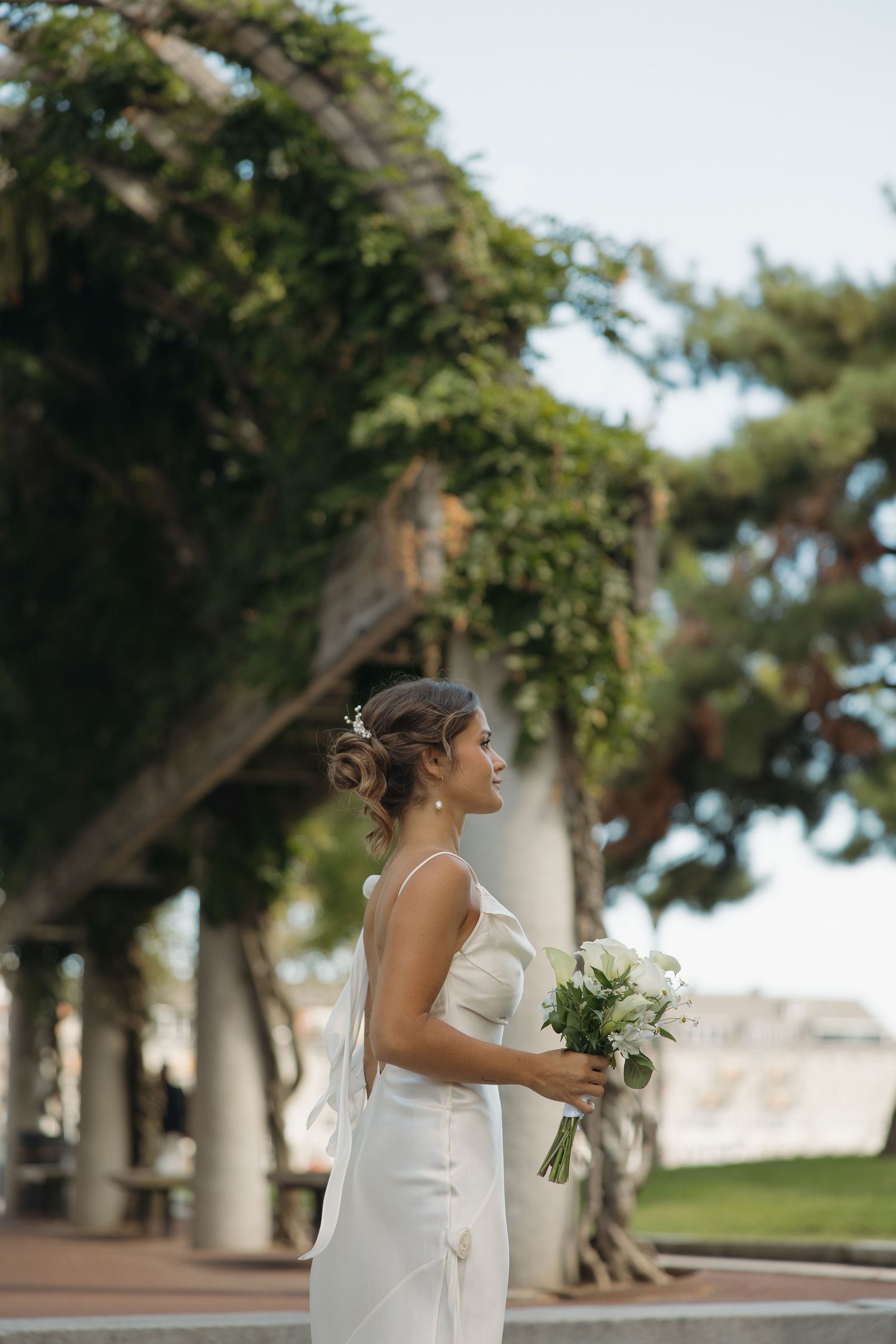 A bride in a flowing white dress walks along a palm tree-lined path on her wedding day.
