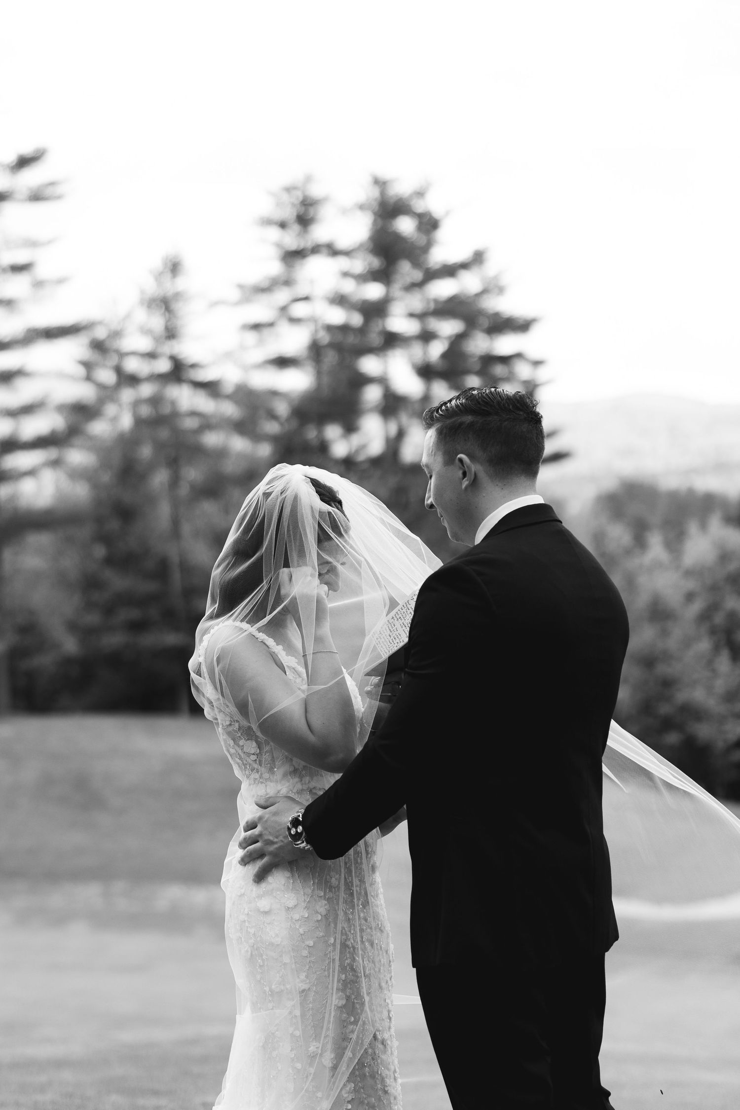 A romantic black and white wedding photo series showing a couple embracing outdoors with trees in the background.