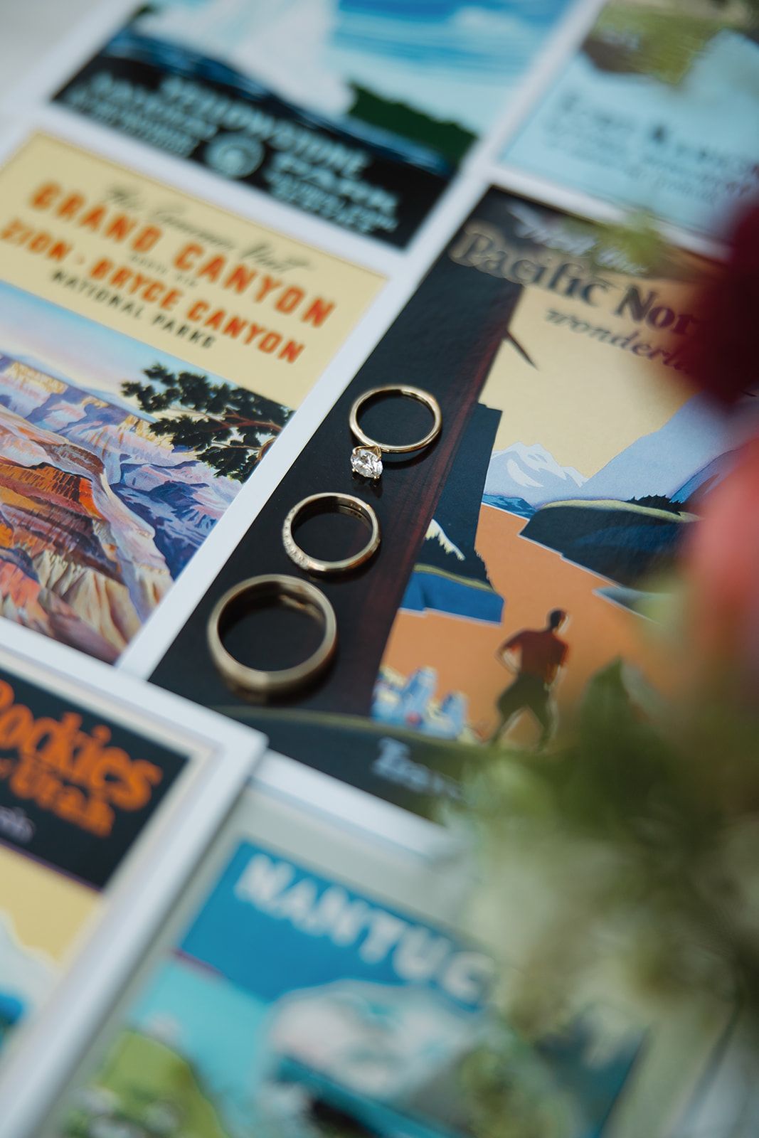 Wedding rings displayed on top of vintage travel posters featuring national parks and scenic destinations.