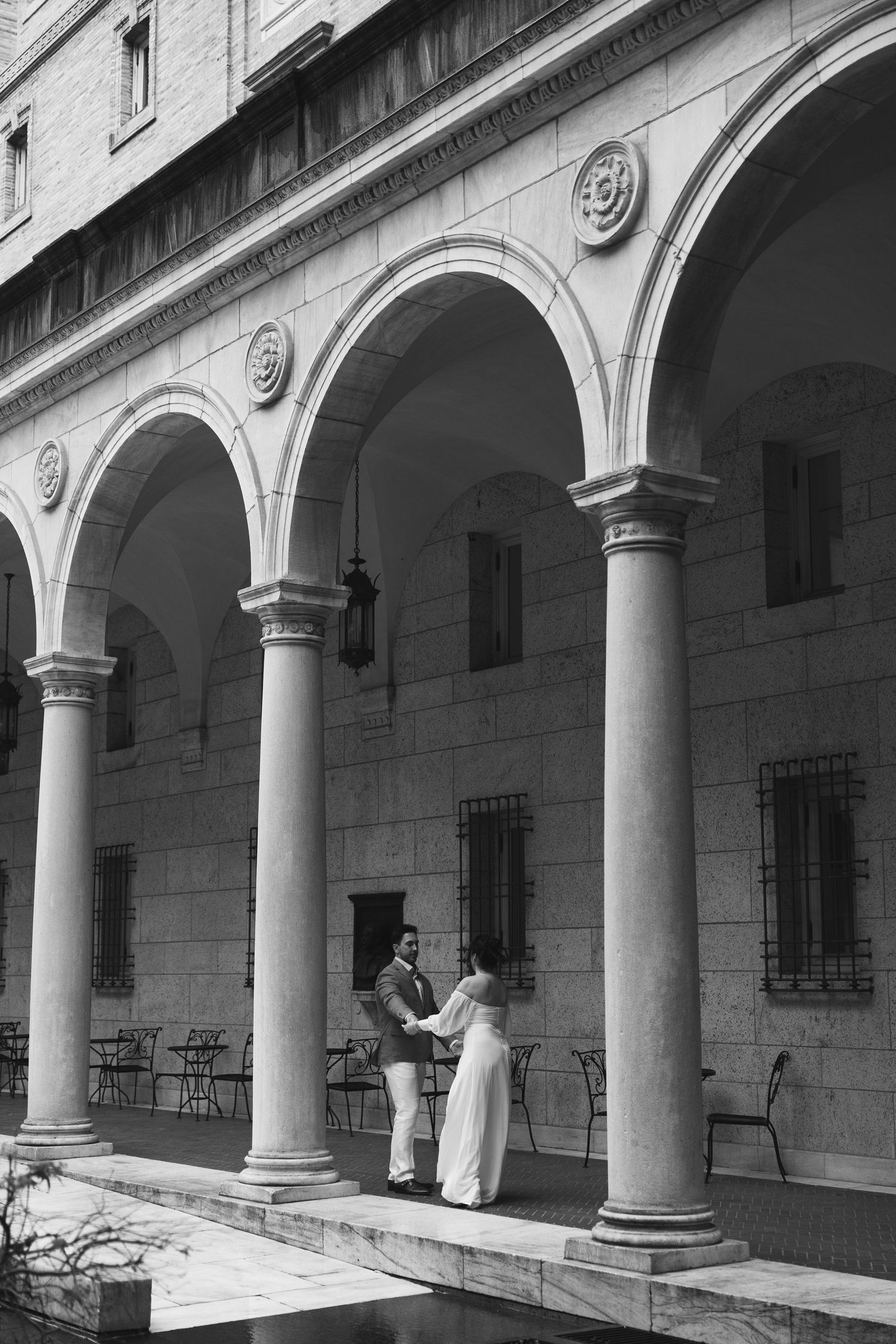 Historic colonnade with white stone arches and columns creates a covered walkway along a building exterior.