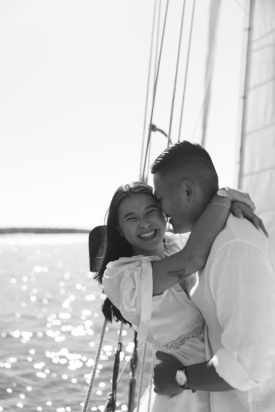 A romantic black and white photo series showing a couple embracing and laughing together by a window.