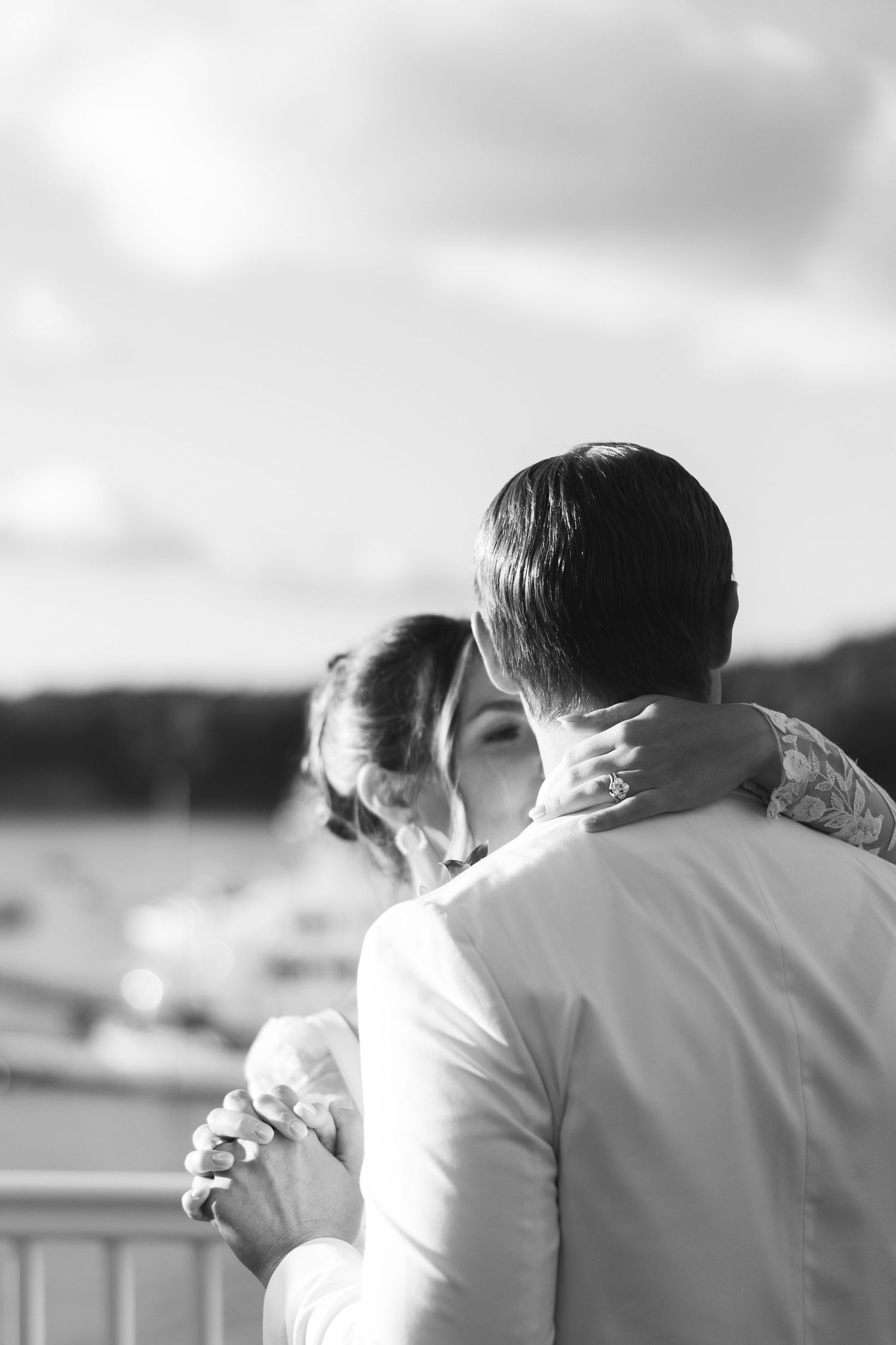 A romantic couple embraces while standing outdoors in black and white photography.