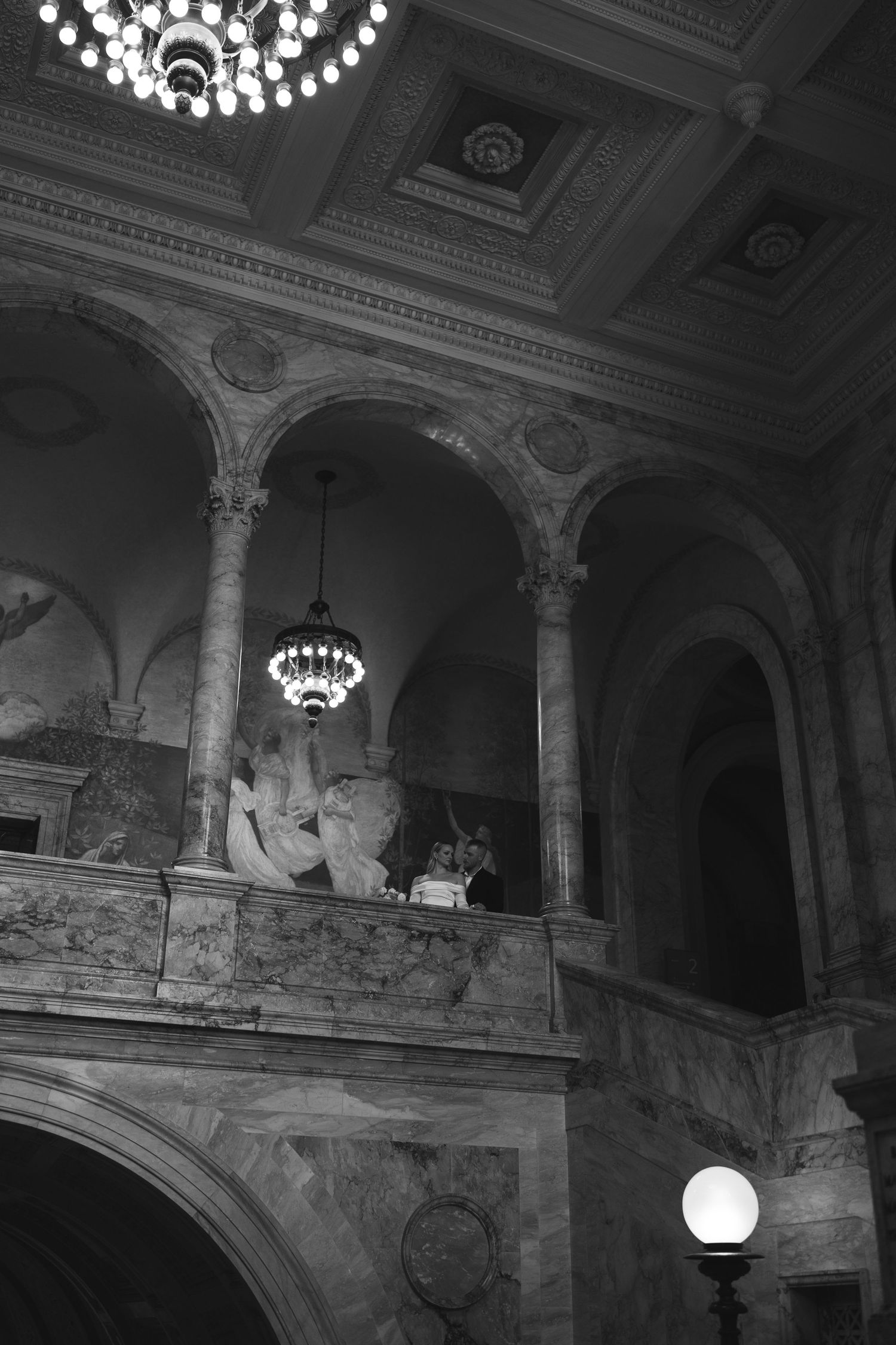 Ornate architectural details of a historic theater interior with arches, columns and decorative lighting fixtures.