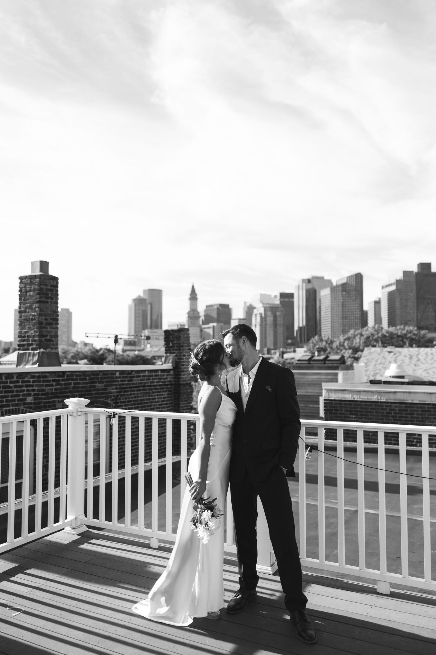 A wedding couple on a rooftop deck with city skyline views in the background.