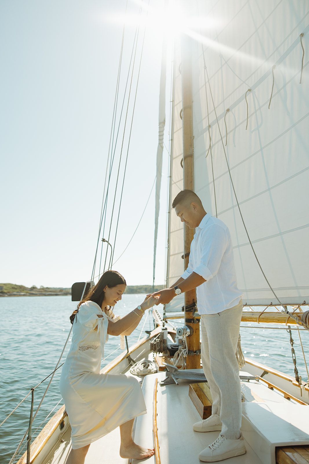 People enjoying a peaceful moment aboard a sailing yacht with white sails in the background.