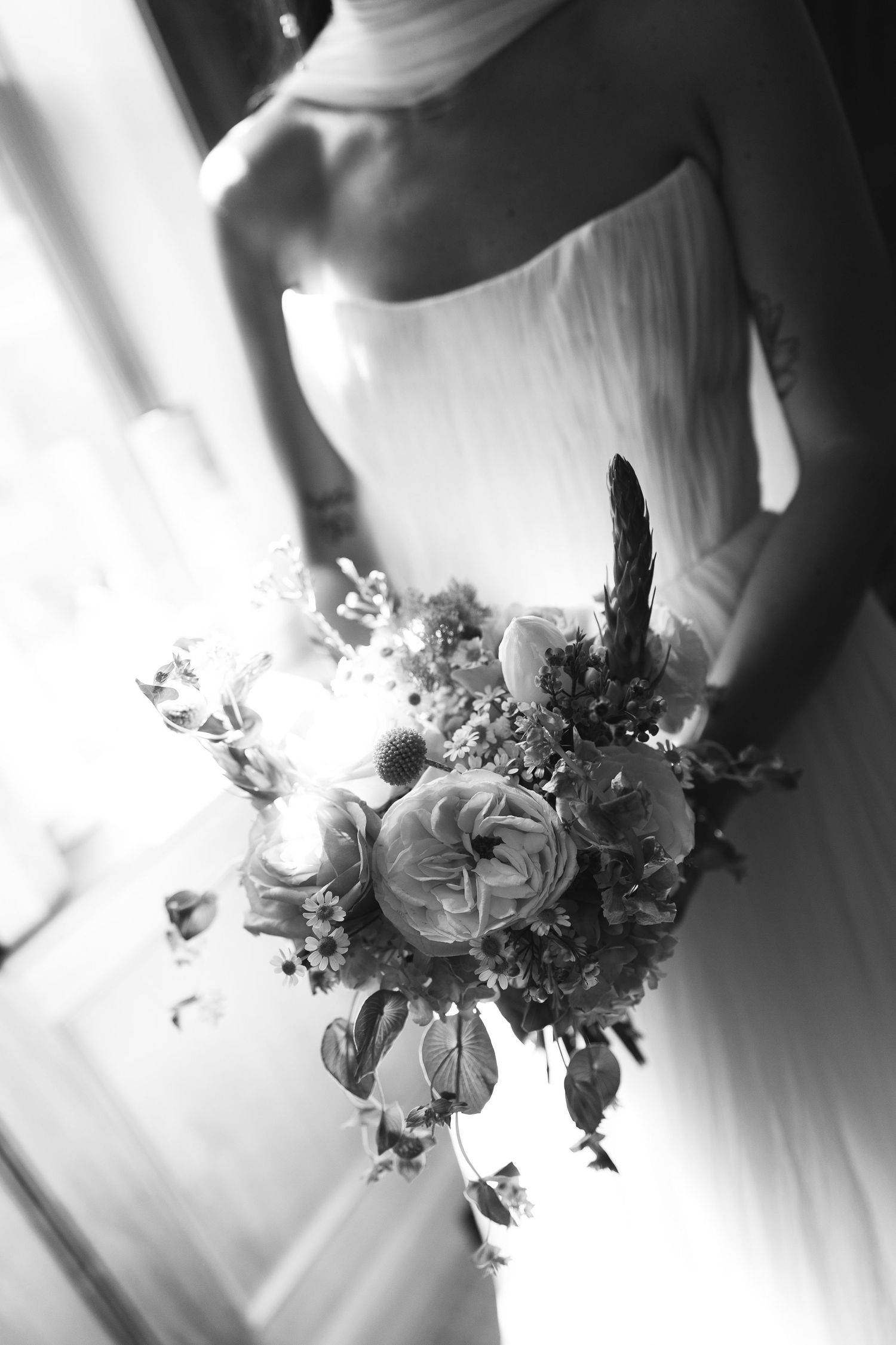 Black and white wedding photo series showing elegant floral bouquets with roses and delicate details against flowing fabric.