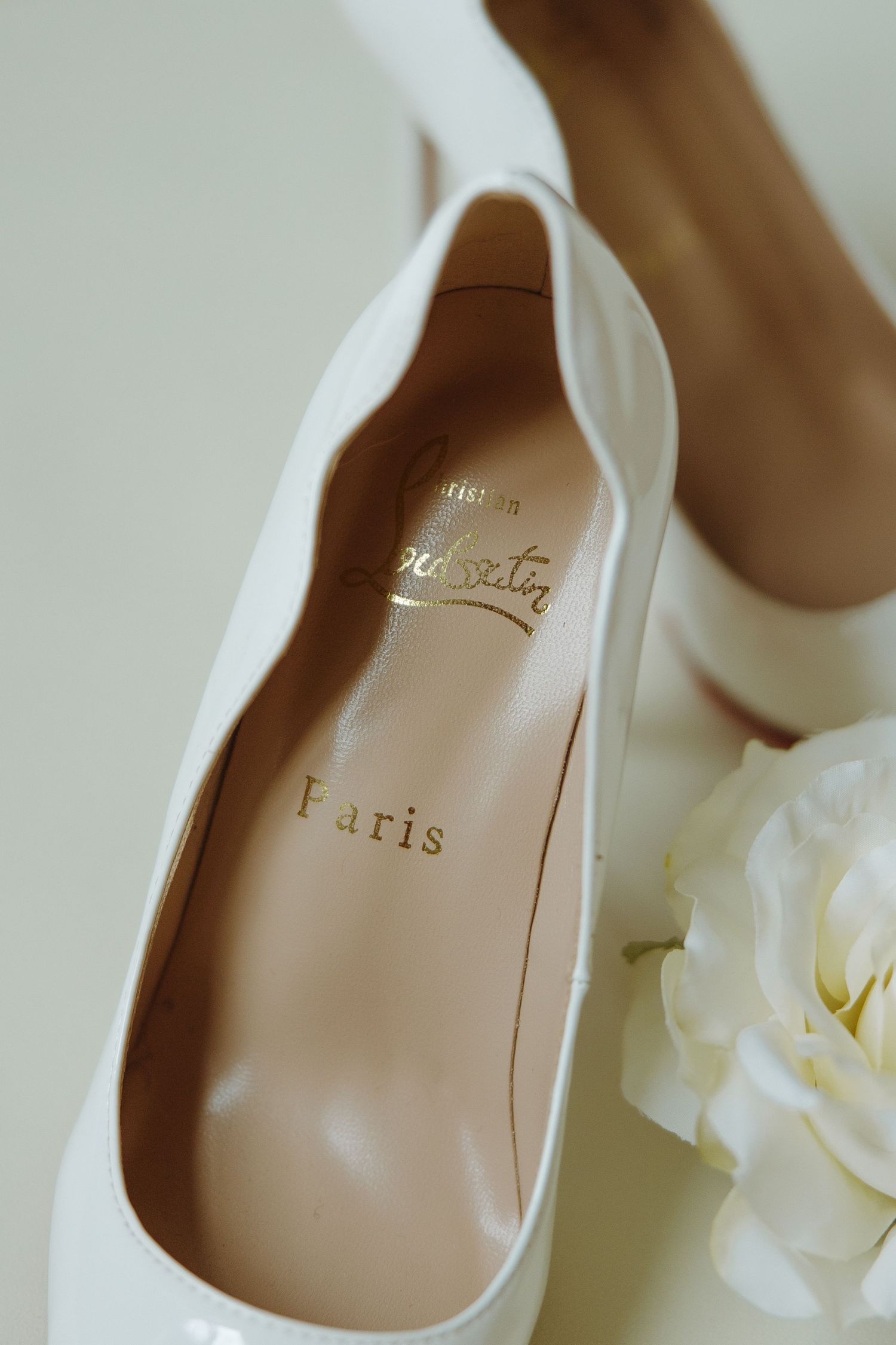 Close-up details of elegant nude-colored bridal shoes with delicate white floral accents.