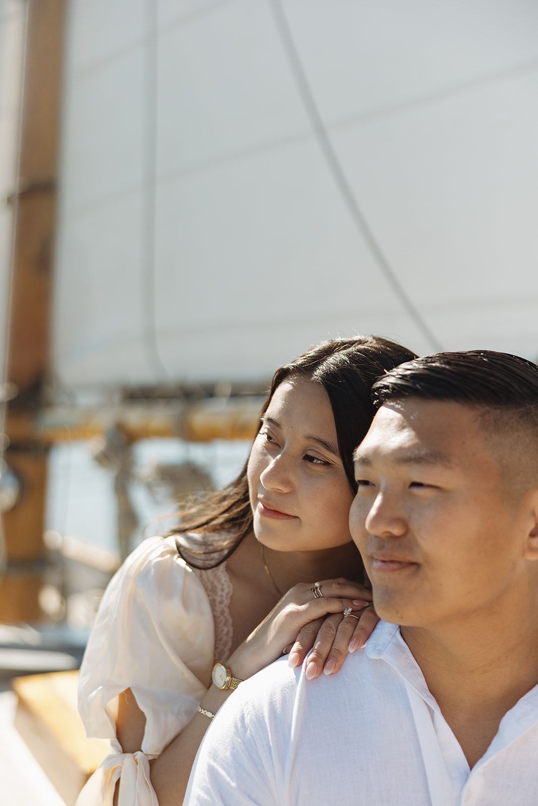 A group of young people sitting together and smiling while looking off into the distance in warm sunlight.