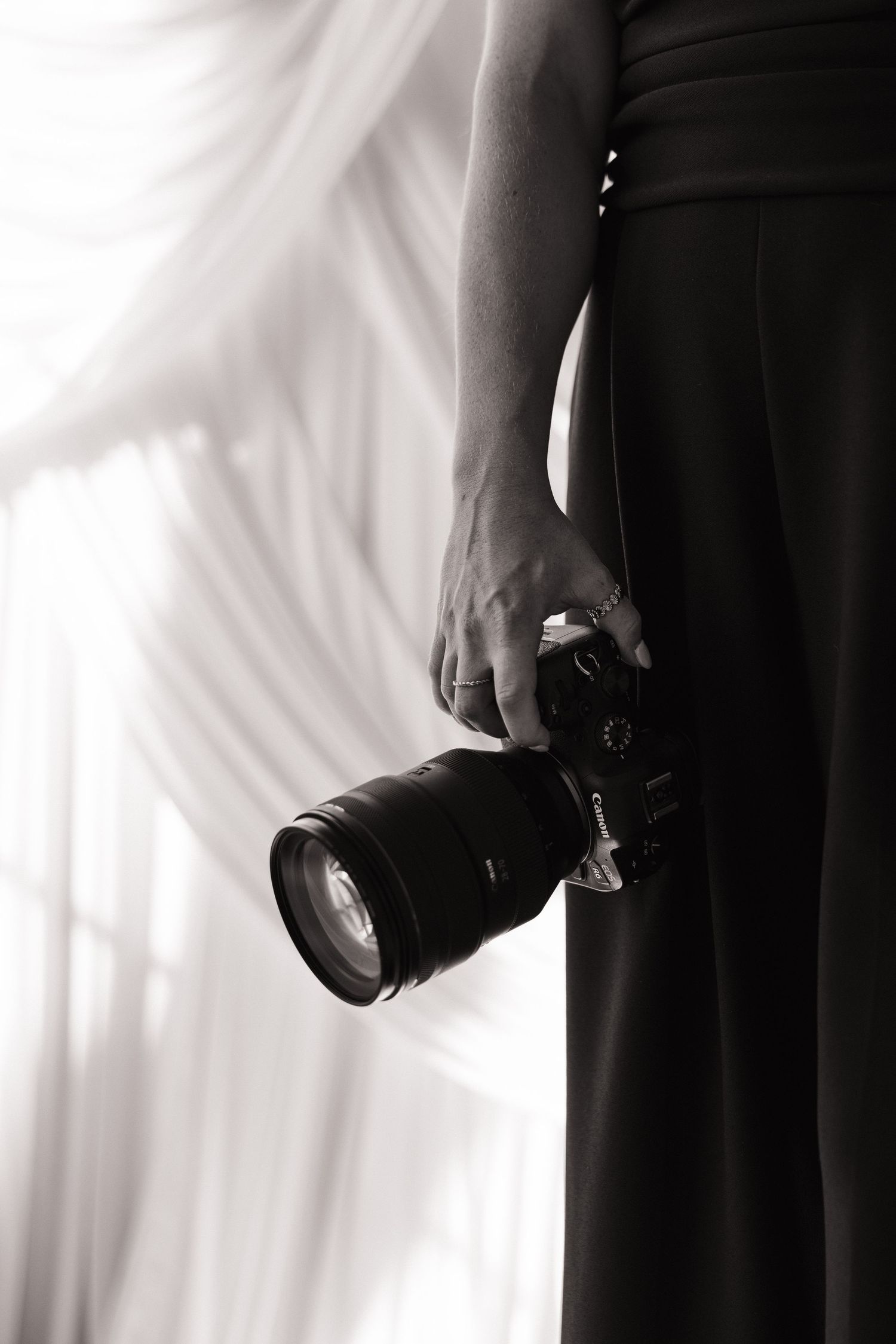 Silhouetted hands holding professional camera equipment against white backdrop.