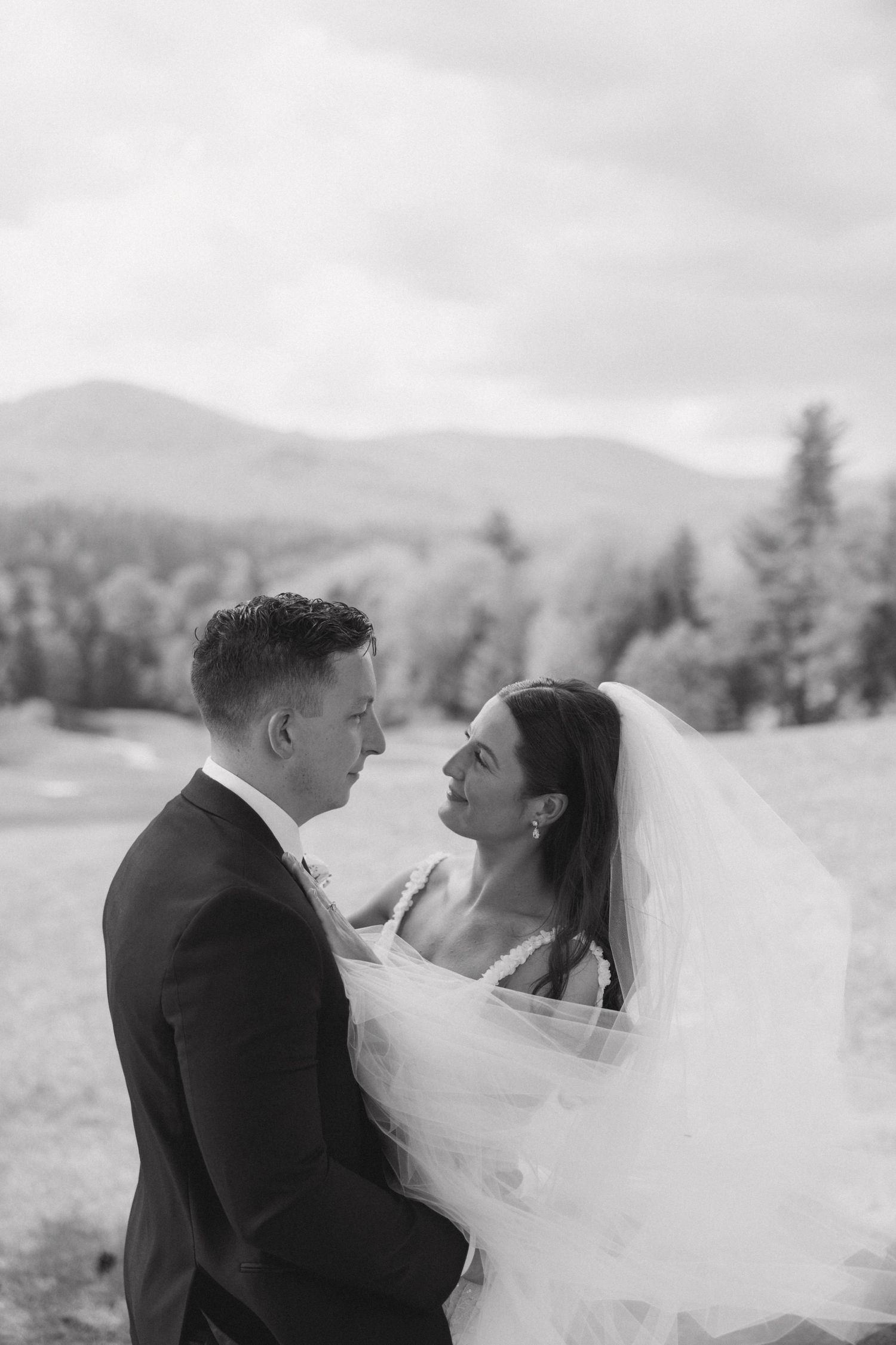 A romantic wedding portrait with mountains and cloudy skies in the background.