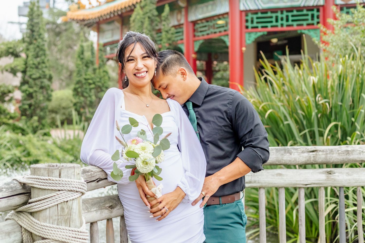 A couple poses for photos after their courthouse elopement in Norfolk, Virginia. The groom is kissing his new wife's sho