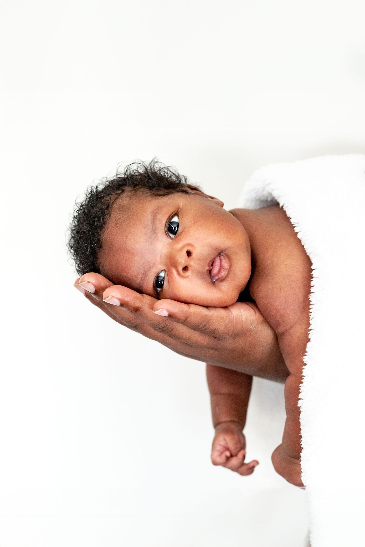 A photograph of a newborn baby laying her head in her father's hand. Taken in Virginia Beach, Virginia.