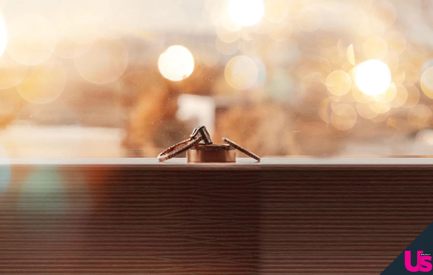 Close-up of elegant diamond engagement ring displayed on a reflective surface with bokeh background.
