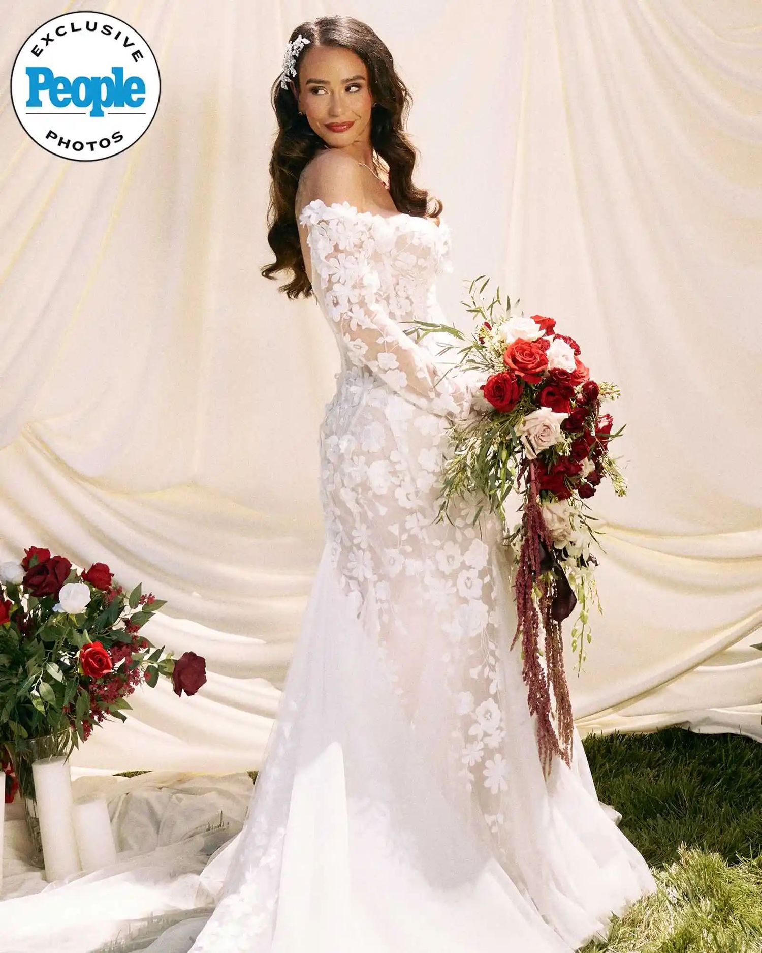 Bride in white lace off-shoulder mermaid gown holding red rose bouquet, featured in People magazine exclusive wedding photos.