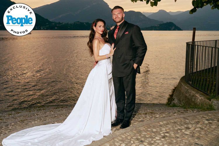 Couple poses in wedding attire by a lake at sunset, bride in white gown, groom in black suit, People magazine exclusive.
