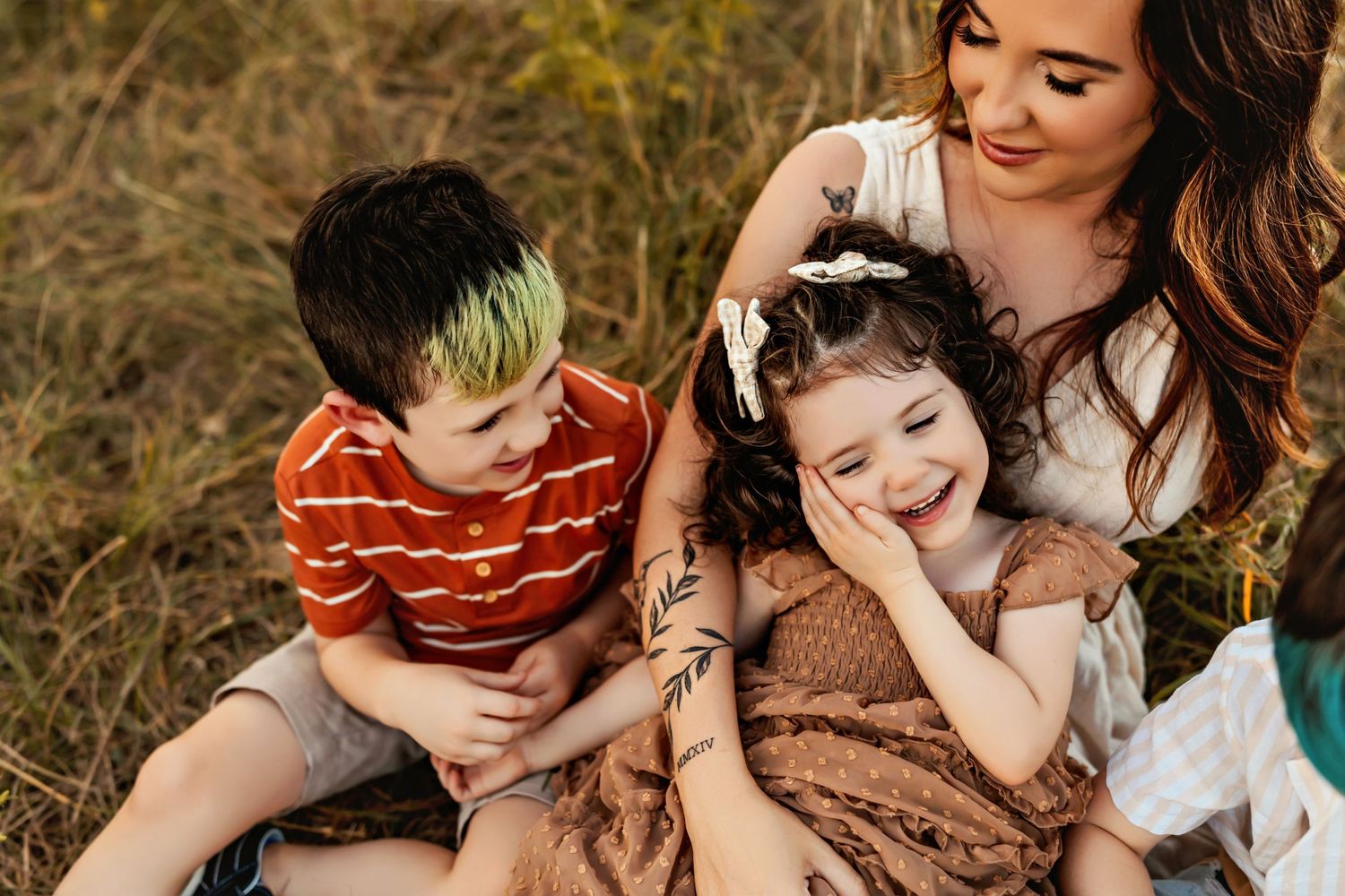 Family enjoying playful outdoor moment together in grassy field at sunset.