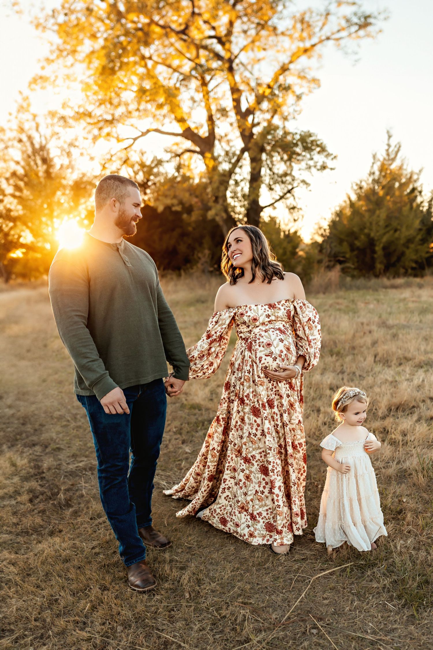 Family shares joyful moment at golden hour in field wearing coordinated autumn colors.