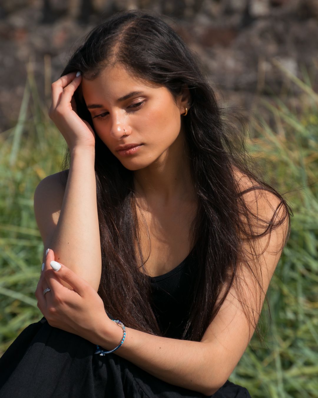 A series of moody outdoor portraits showing a woman with long dark hair in contemplative poses against a natural backdrop.