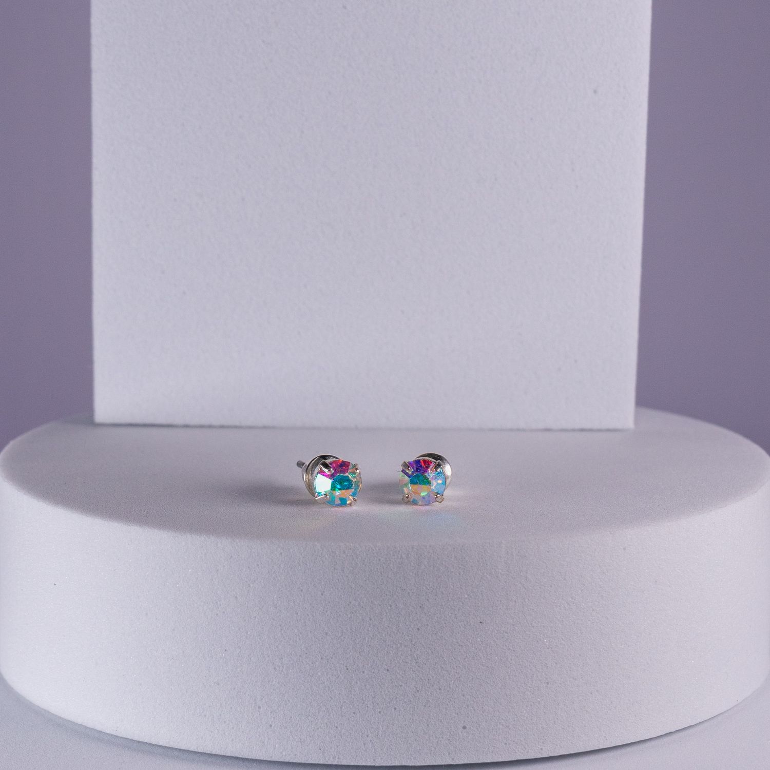 Small aurora borealis crystal stud earrings with rainbow iridescent sparkle displayed on a white pedestal.