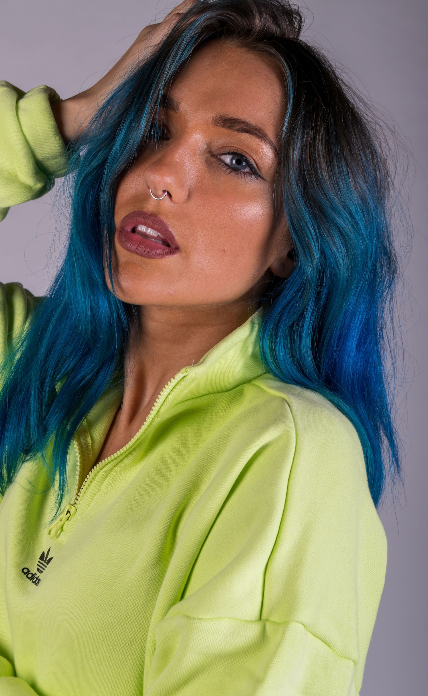 Fashion portrait with vibrant blue hair and neon yellow zip-up jacket.