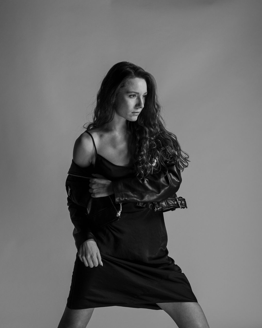 A dramatic black and white photo series showing a figure in a black top with flowing dark hair in motion against a gray backdrop.
