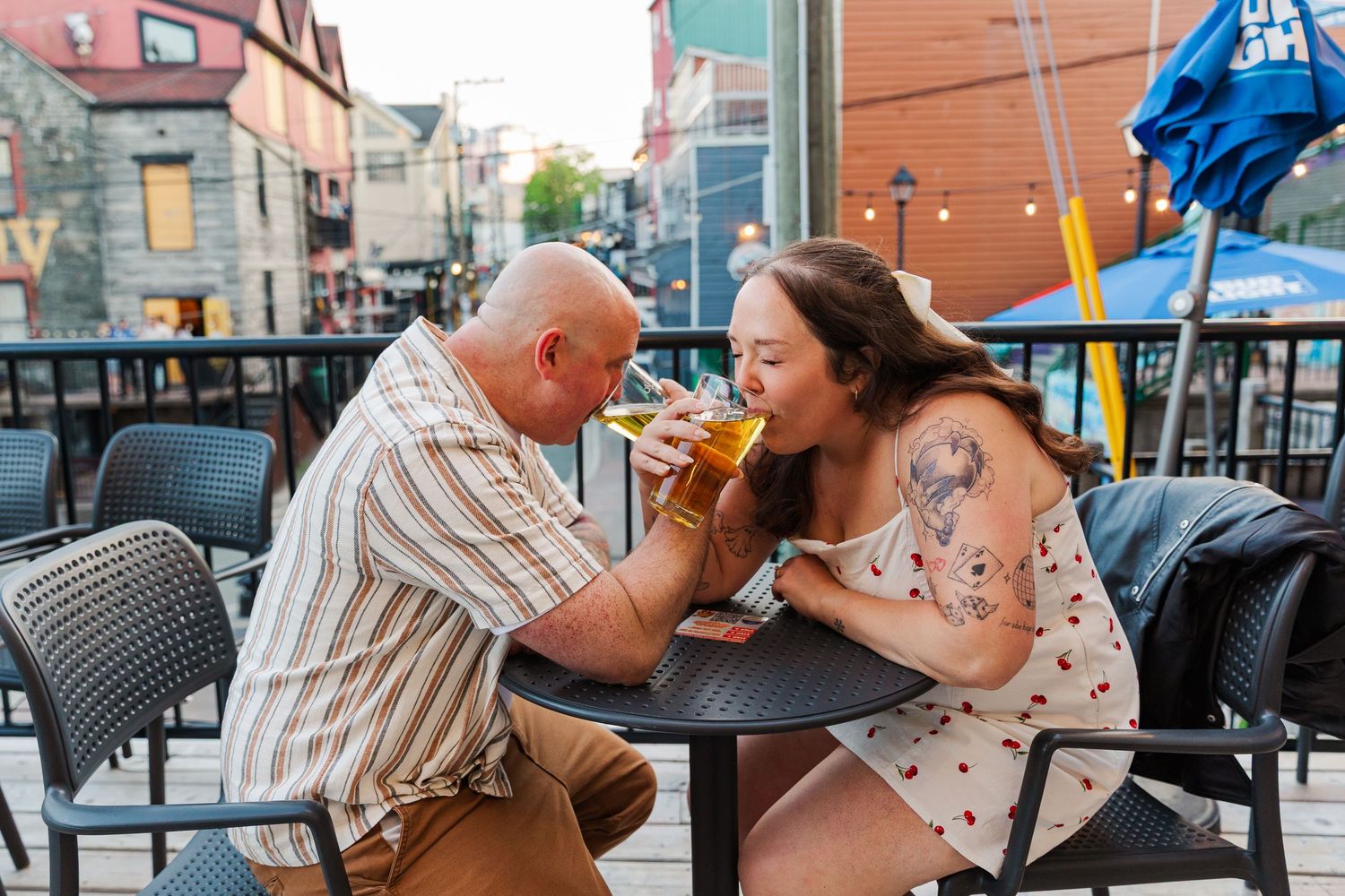 Downtown St.John's Engagaement Session. Man and Woman sat at a Table in Trinity Pub Drinking a Quidi Vidi Brewery Iceberg beer.