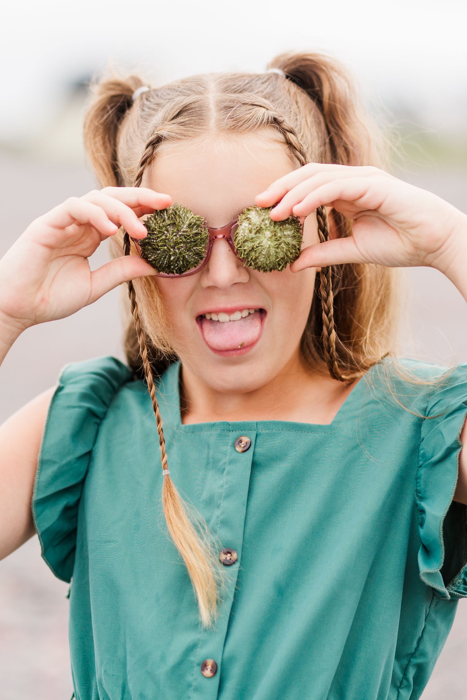 Woman in teal blouse holding green rolls over eyes in playful poses across sequence of candid photos.