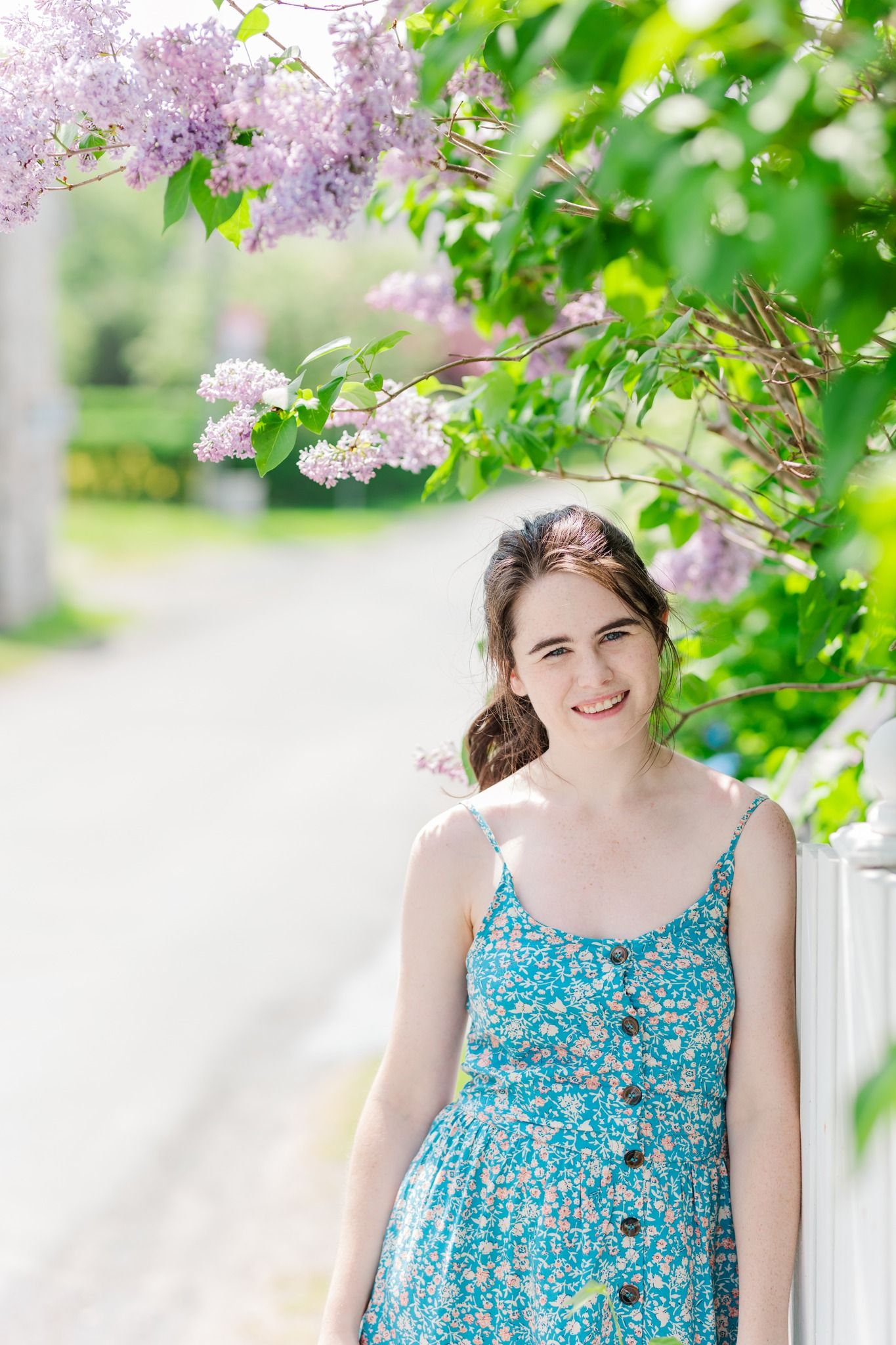 A floral blue sundress worn under blooming lilac branches on a bright spring day.