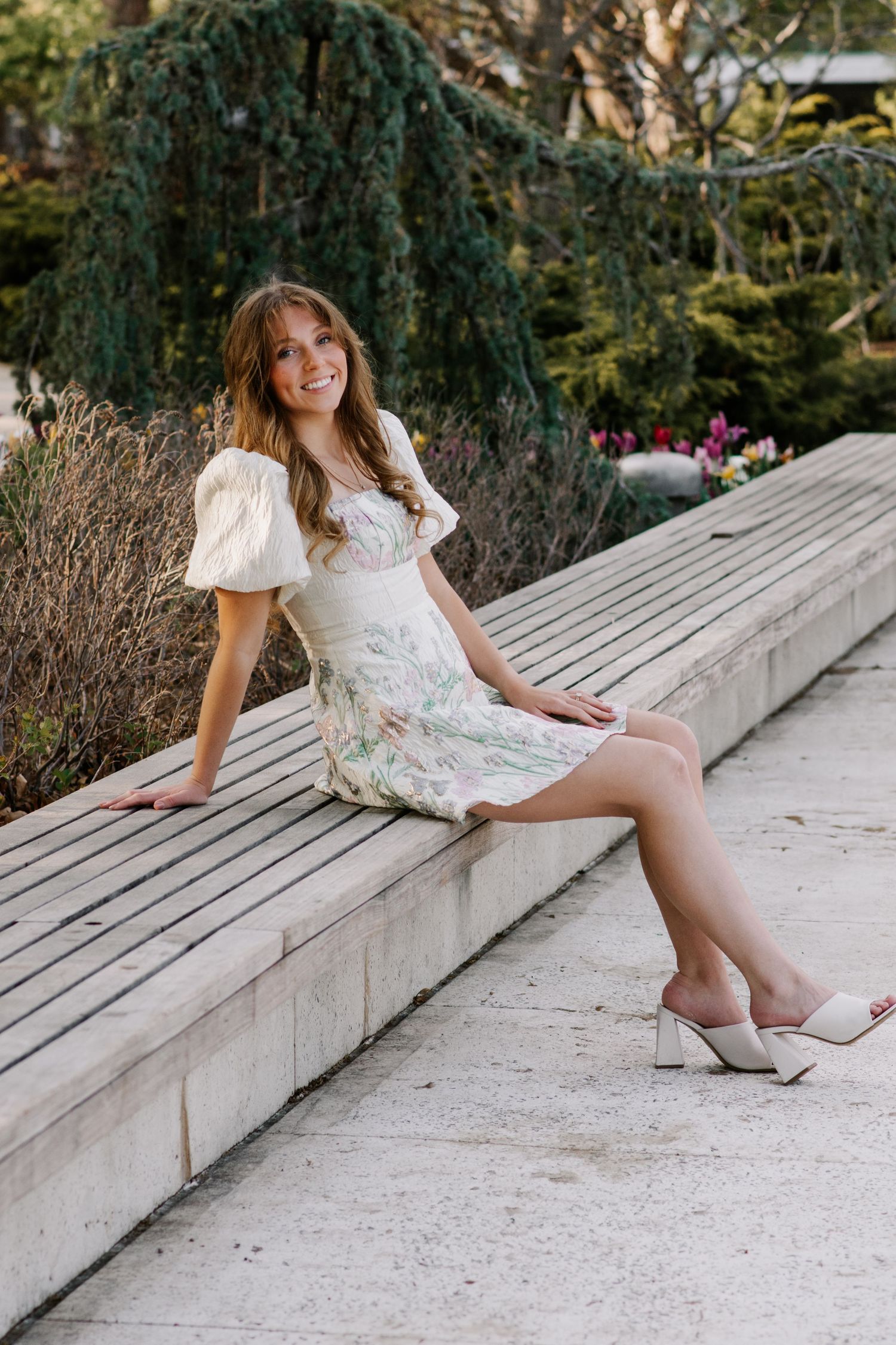 college senior posing on a wooden bench at Myriad Botanical Gardens in Oklahoma City, Oklahoma