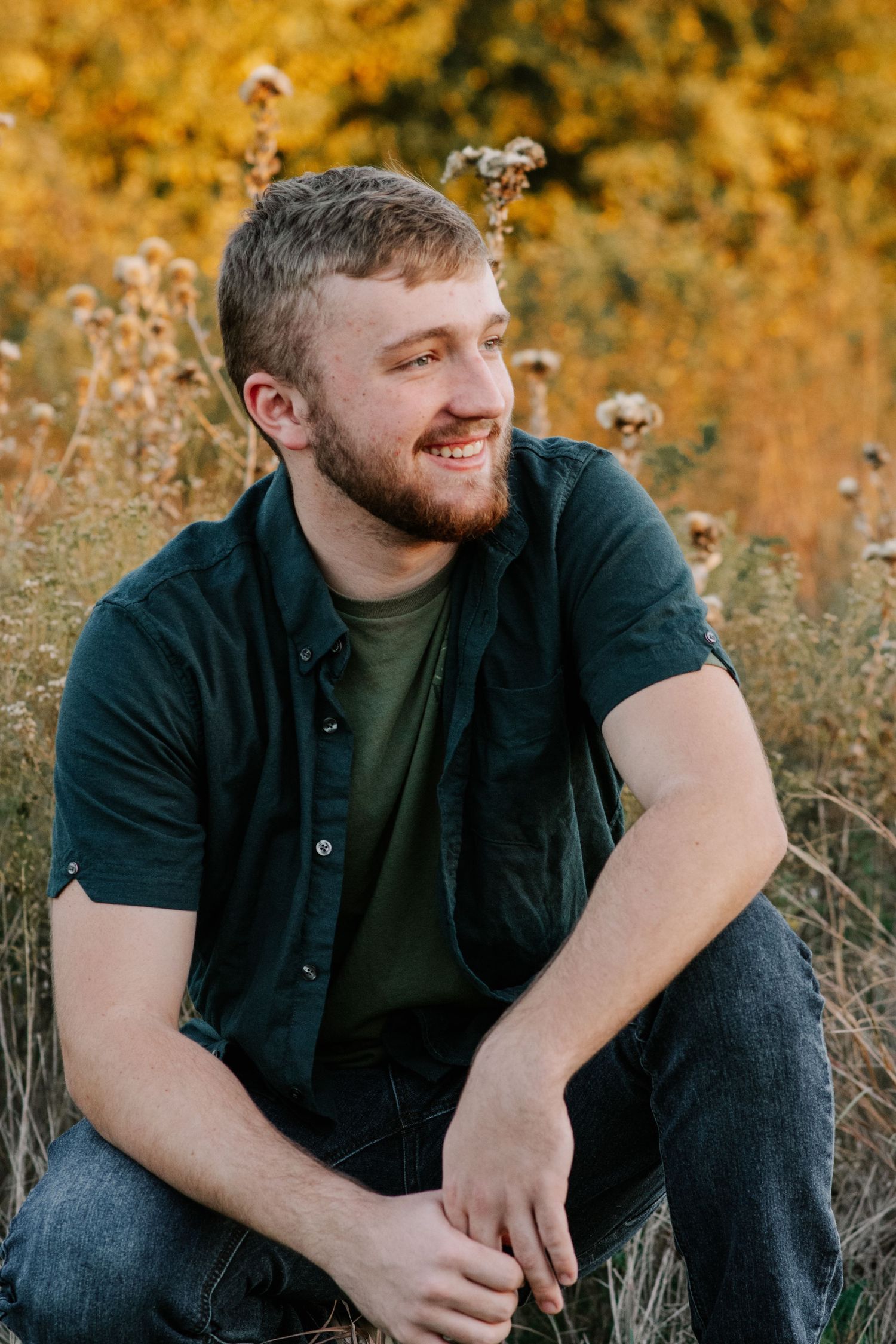 Senior posing in a field at golden hour at George M. Sutton Wilderness Park in Norman Oklahoma