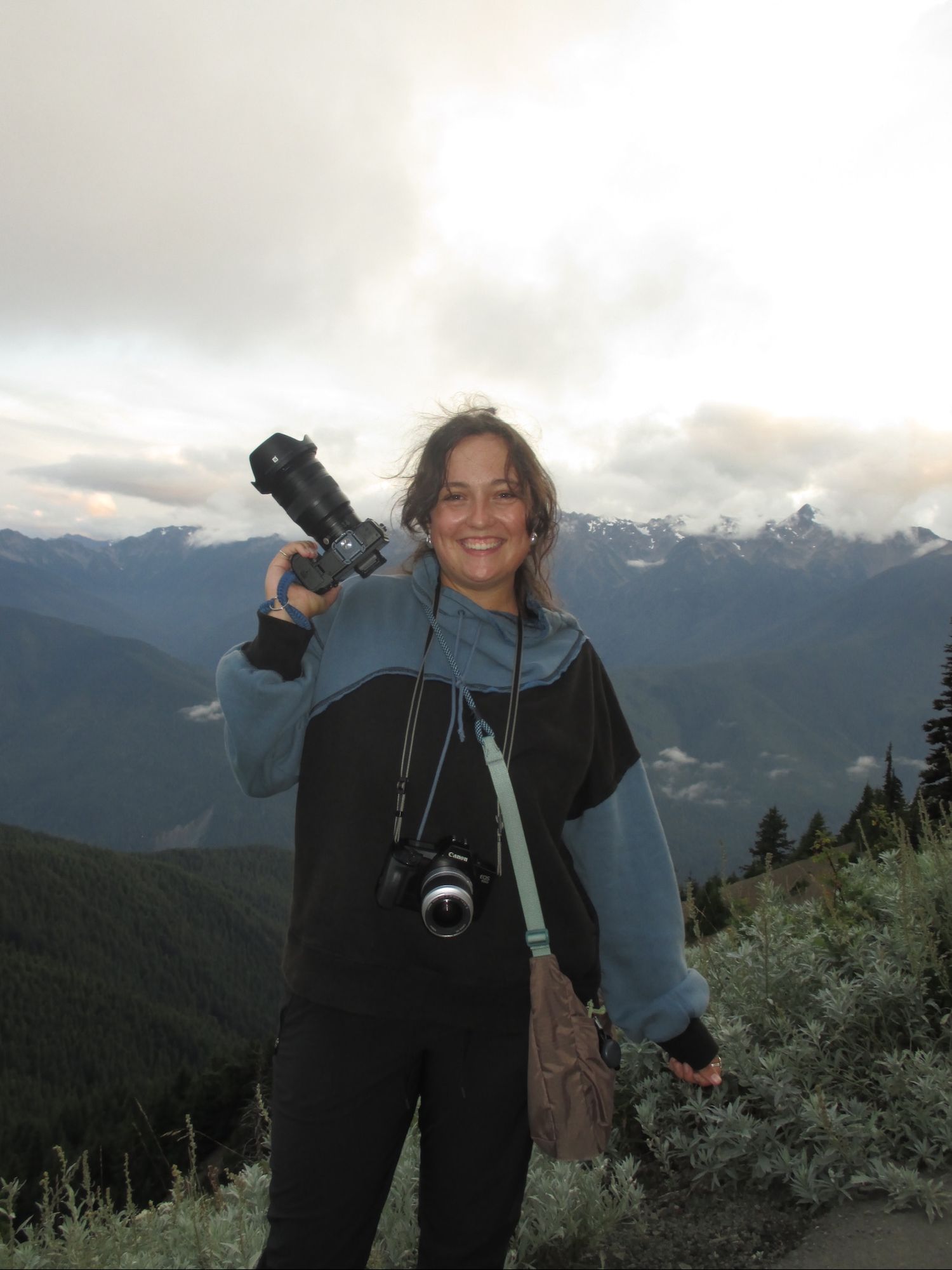 Photographer smiling in front of Olympic Mountains on the Hurricane Ridge trail in Olympic National Park, Washington.