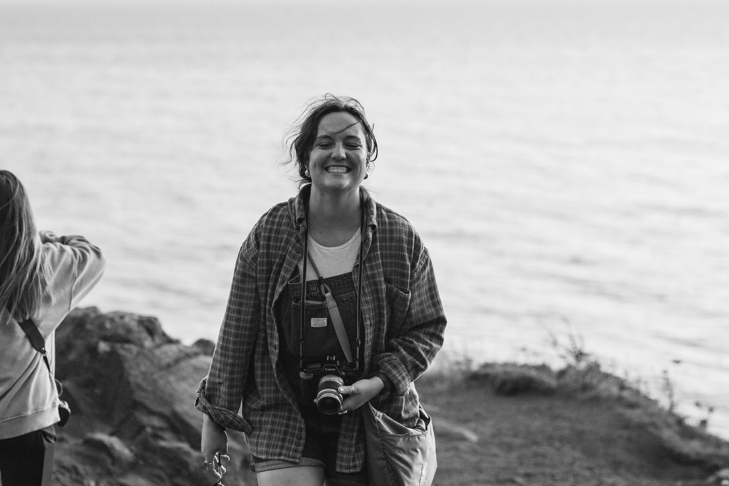Girl with a camera smiling while standing on a cliff at Elk Flats, Oregon.