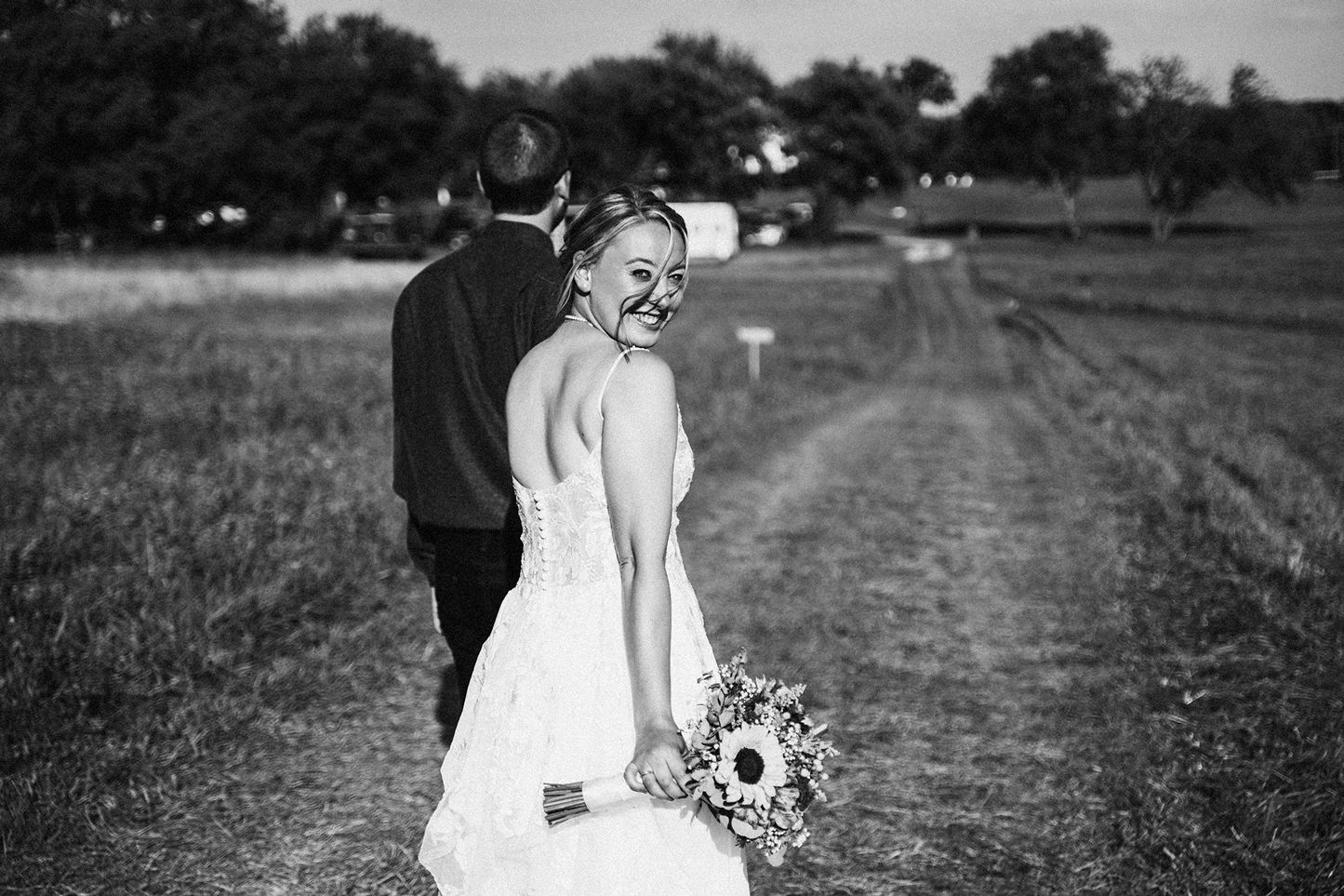 A collection of black and white wedding photos showing couples embracing on a rustic outdoor path.