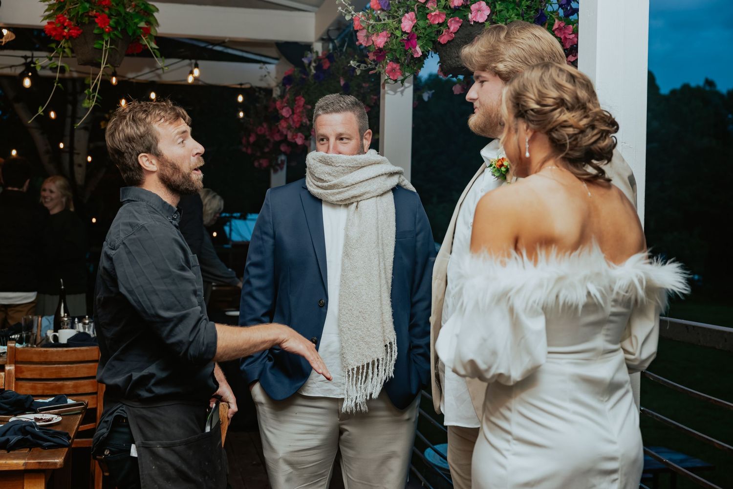 Evening wedding reception on outdoor patio with string lights and floral decorations.