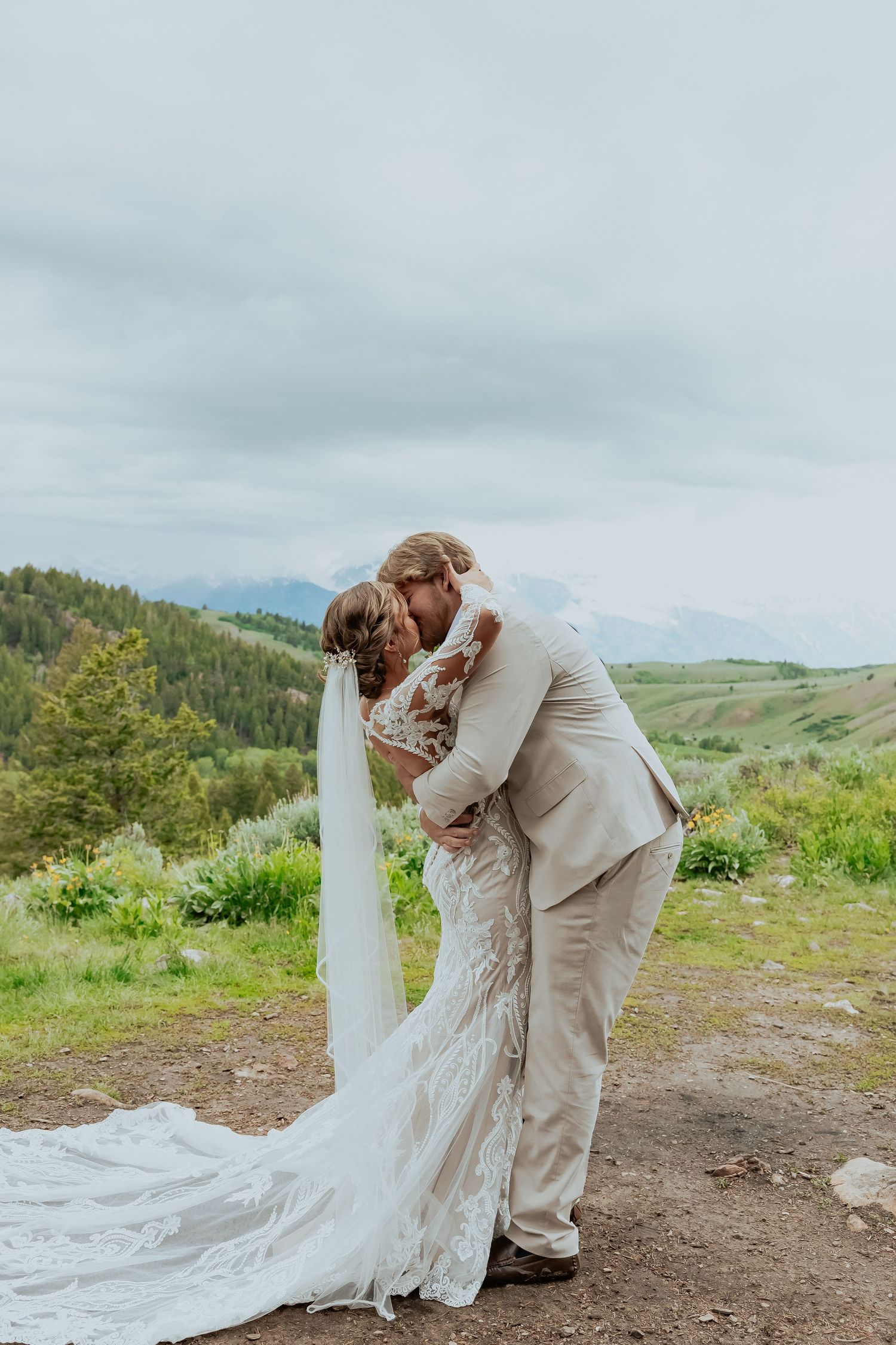 Intimate wedding moment captured against a backdrop of mountain peaks and summer greenery.
