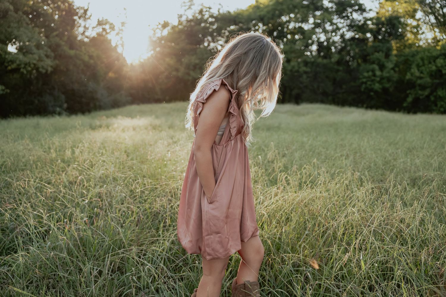 Romantic sunset photoshoot in a grassy field with warm golden light.