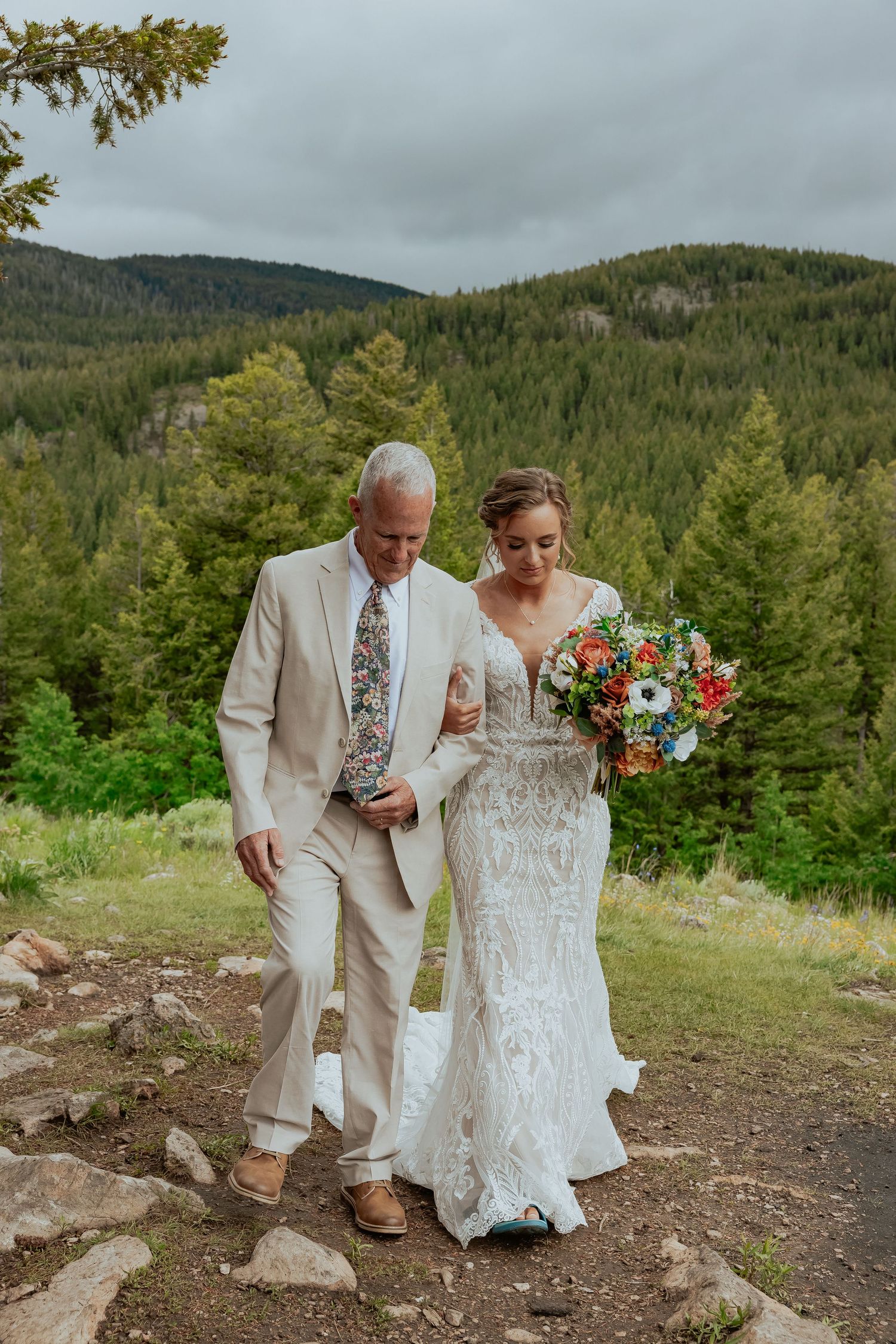 Elegant outdoor wedding ceremony on a mountain trail with pine forests and distant peaks.