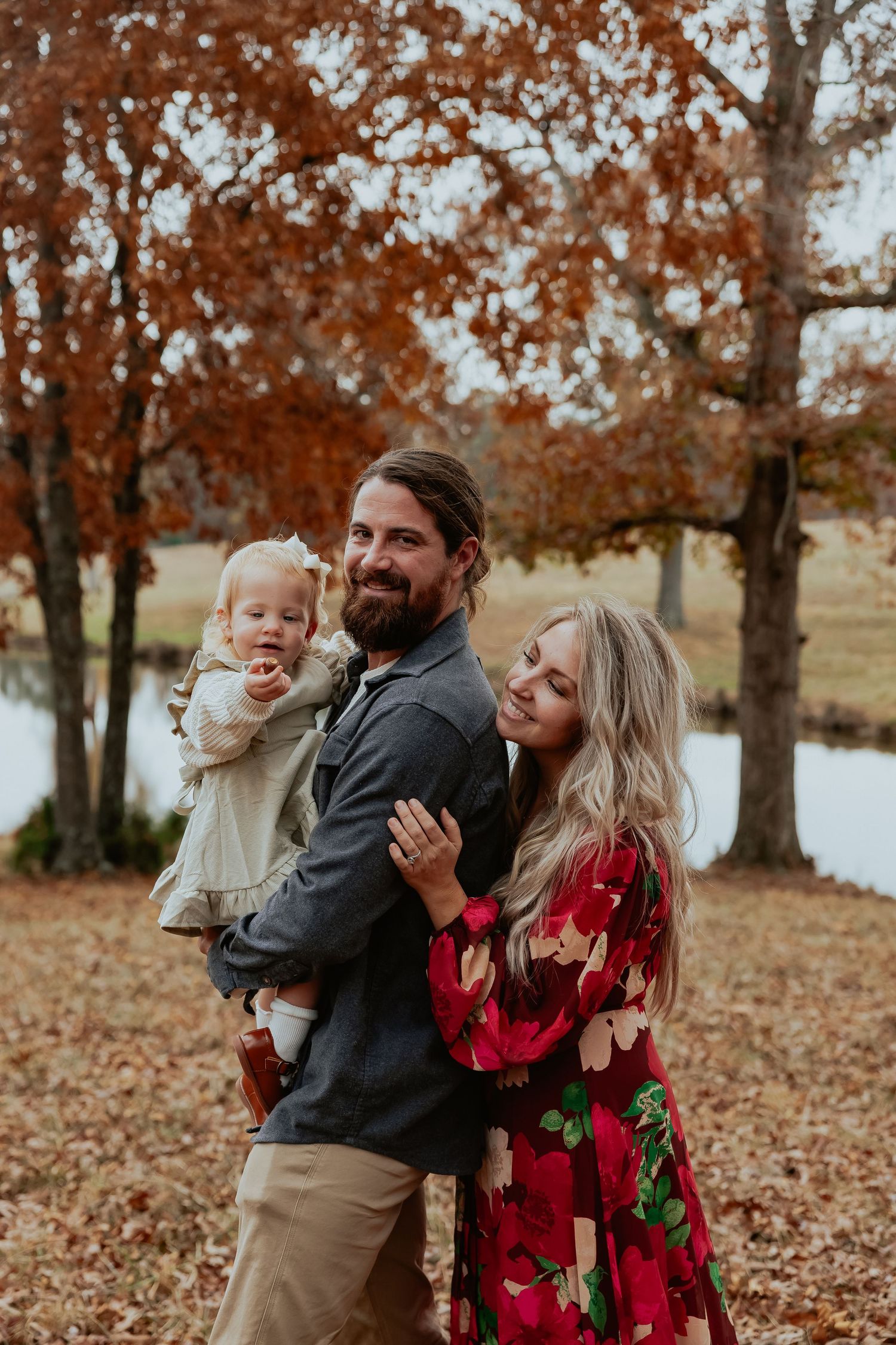 Family enjoying autumn moments together under trees with fallen leaves.