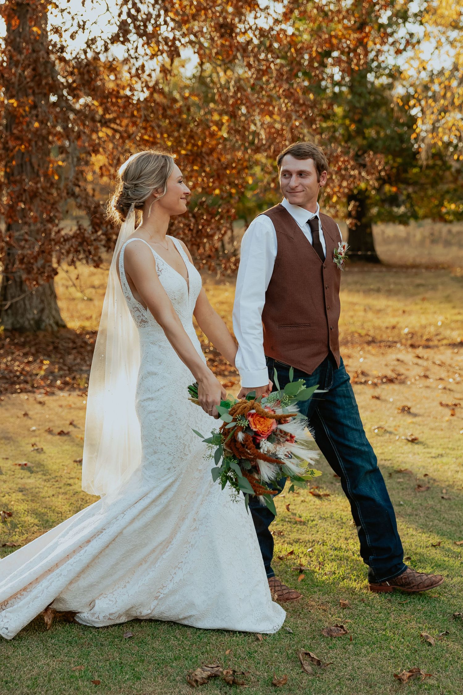 Autumn wedding photos in fallen leaves with bride in white gown.