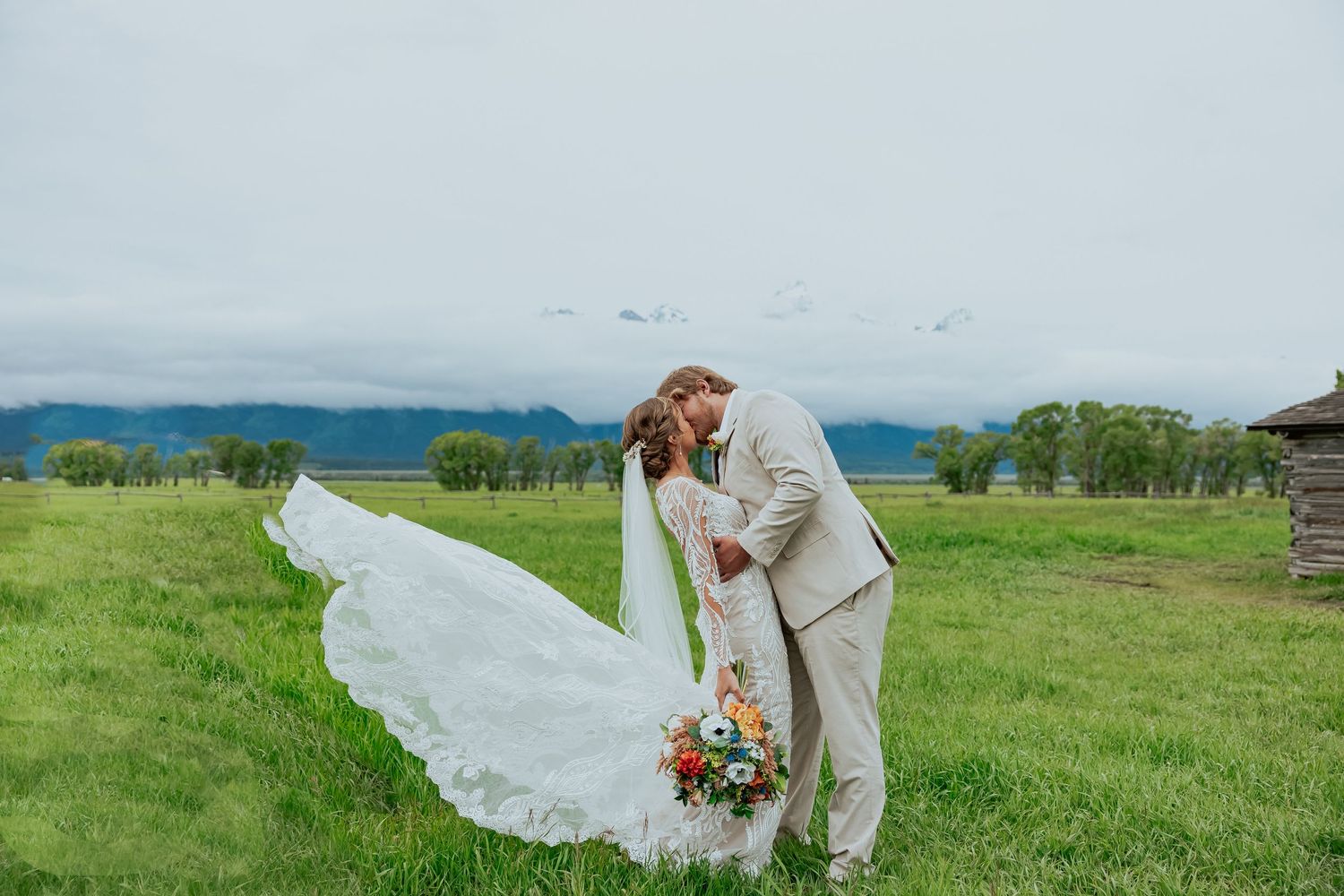 A white wedding dress billows in the wind against a scenic mountain landscape.