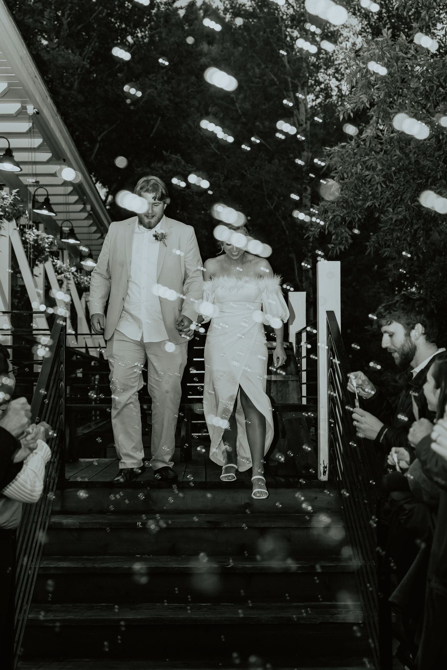 Wedding party members walk down stairs during an evening celebration.