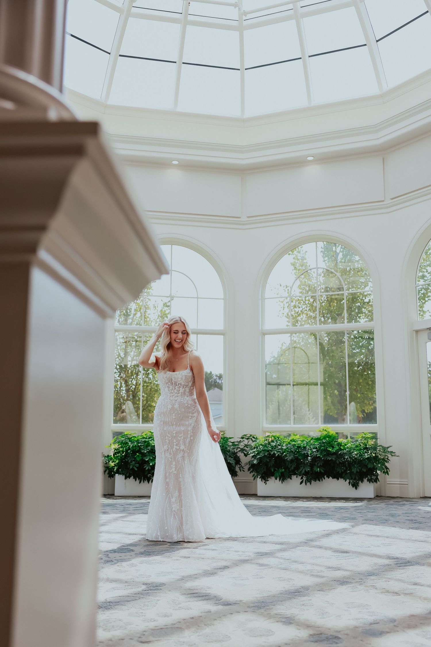 Wedding dress on display in elegant white conservatory with domed glass ceiling.