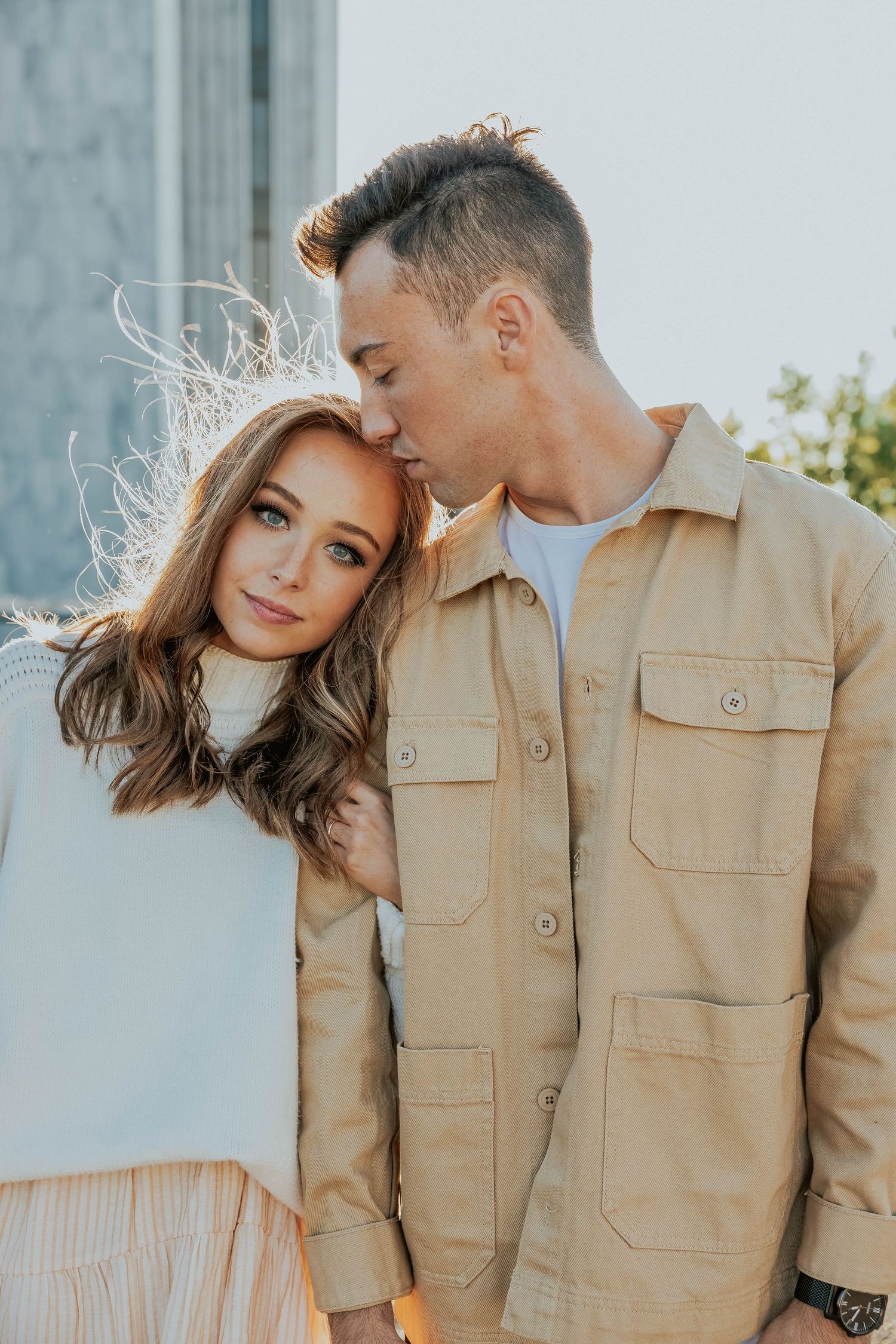 Romantic couple in neutral tones share intimate moments against light background.