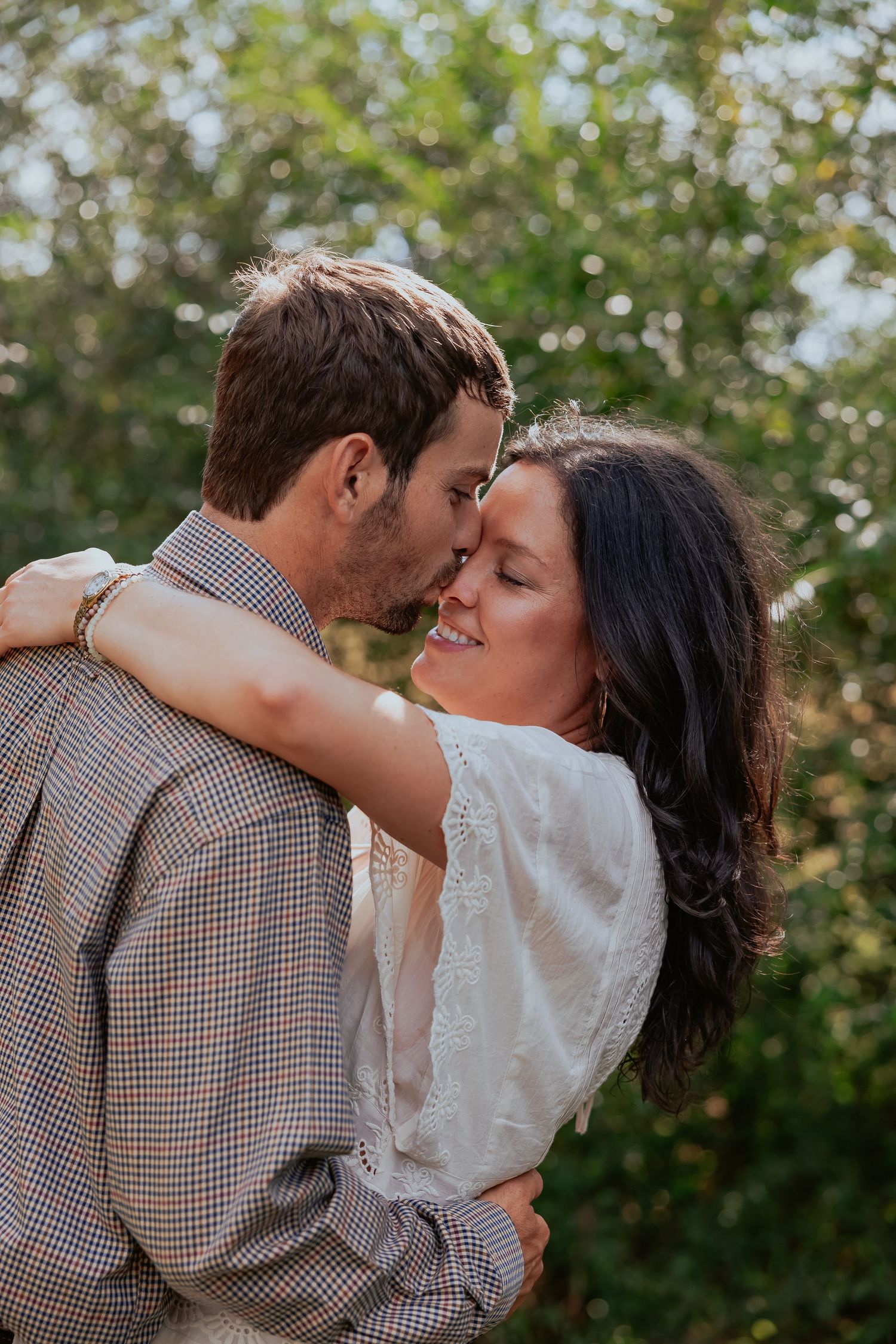 A romantic couple embraces outdoors in a series of intimate poses against a soft green natural background.